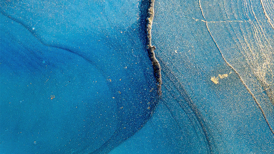 Close-up of a cracked blue surface with specks of yellow and gold dust.