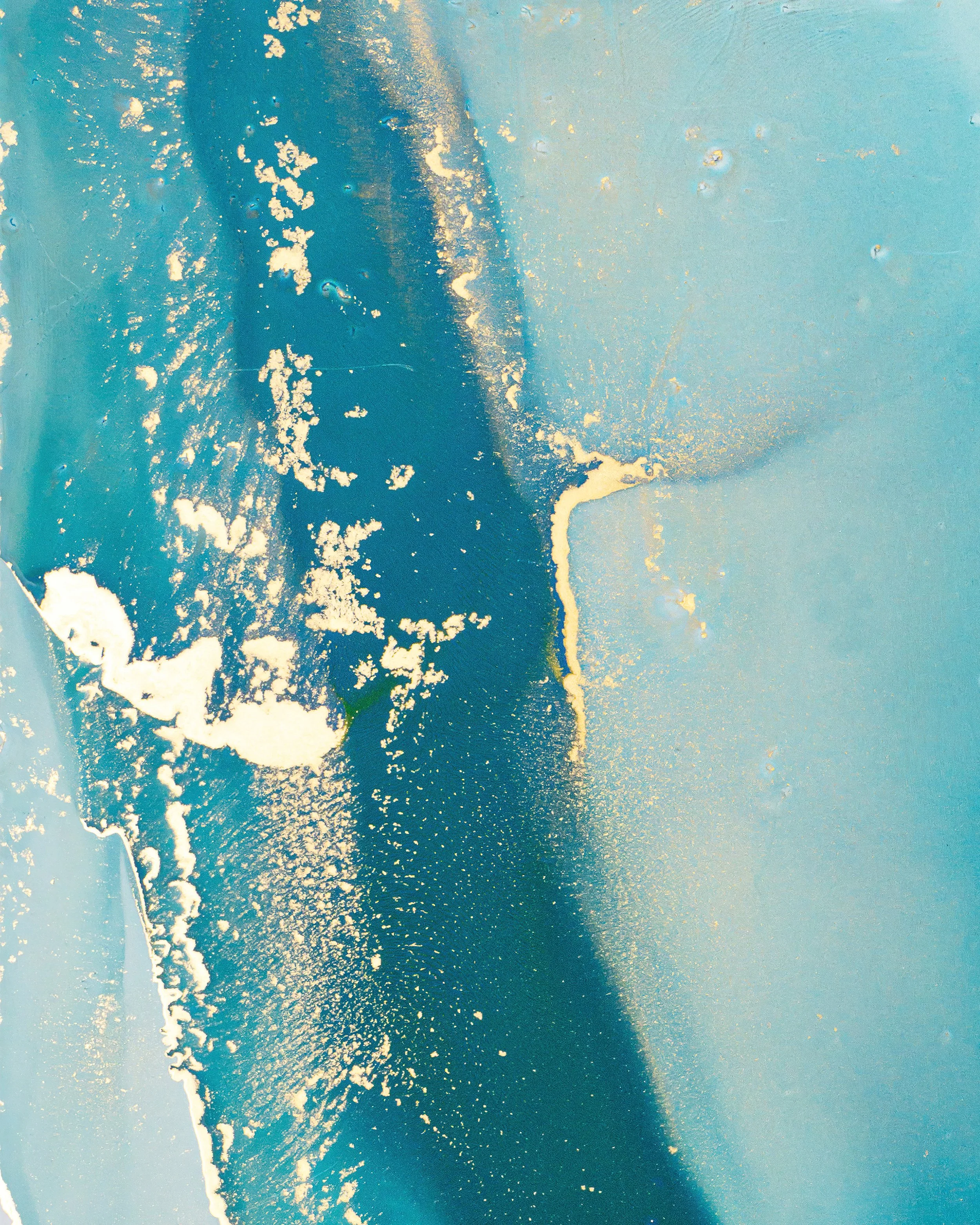 A view of ocean waves with white surf crashing onto a beach, seen from above, under a clear sky.