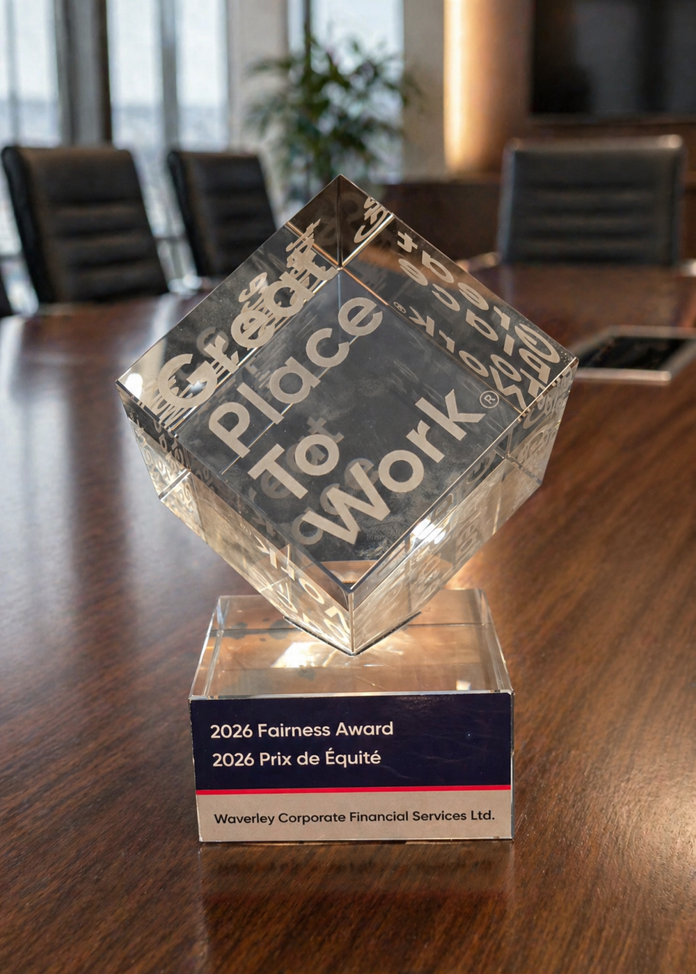 A clear glass award with engraved text, sitting on a wooden conference table. The award is titled '2026 Fairness Award' and '2026 Prix de Équité,' presented to Waverley Corporate Financial Services Ltd.