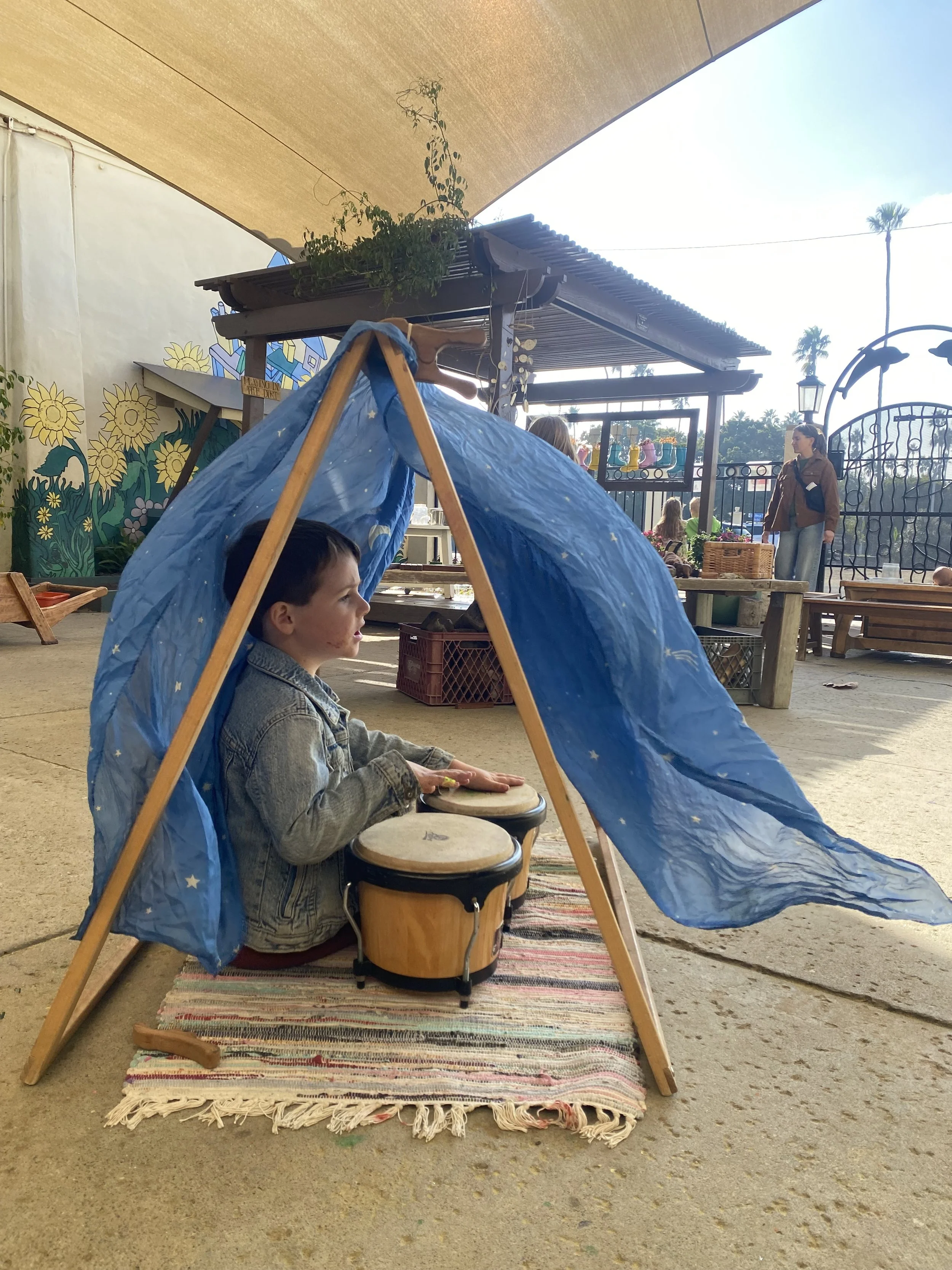 Child playing drums under tent. 