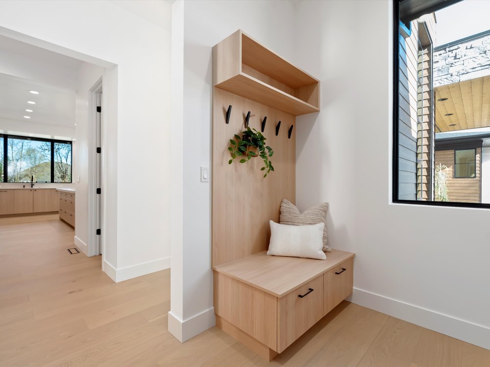 Eagle, Idaho - Eco Builders Modern entryway with wooden bench, wall hooks, and decorative plants