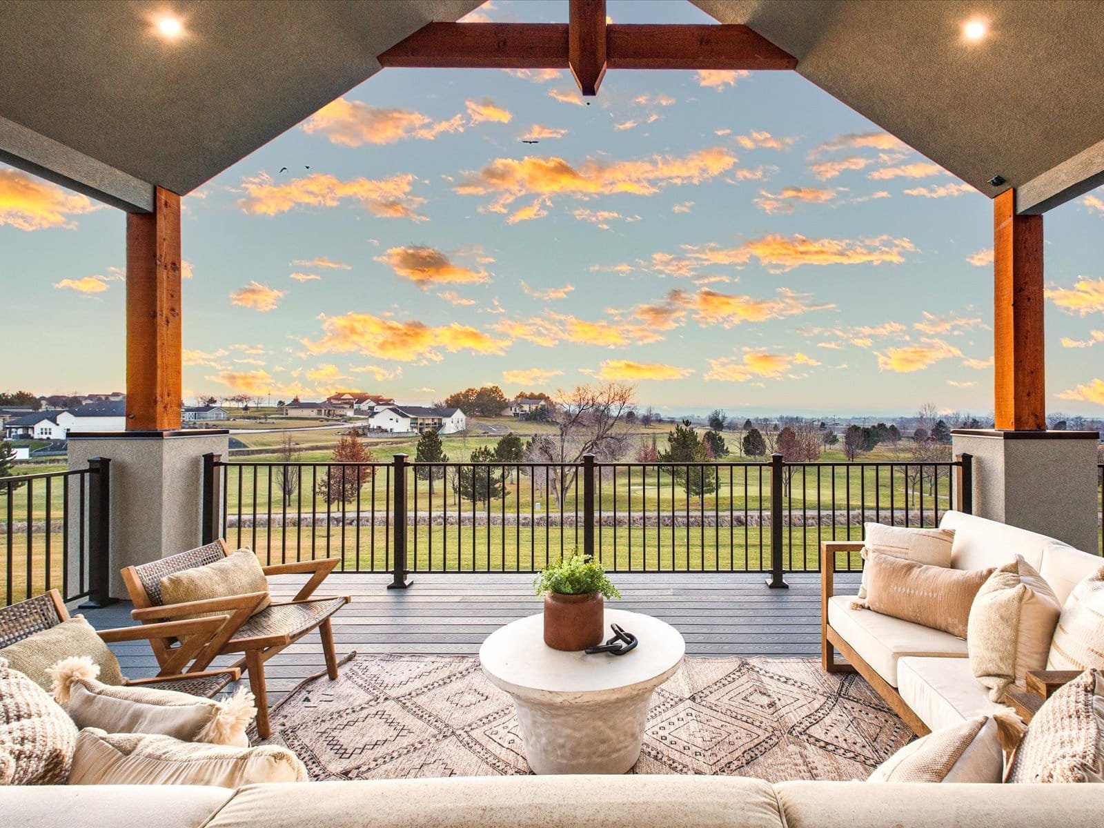 Homes, LLC Outdoor patio with furniture overlooking a scenic landscape with a sunset sky.