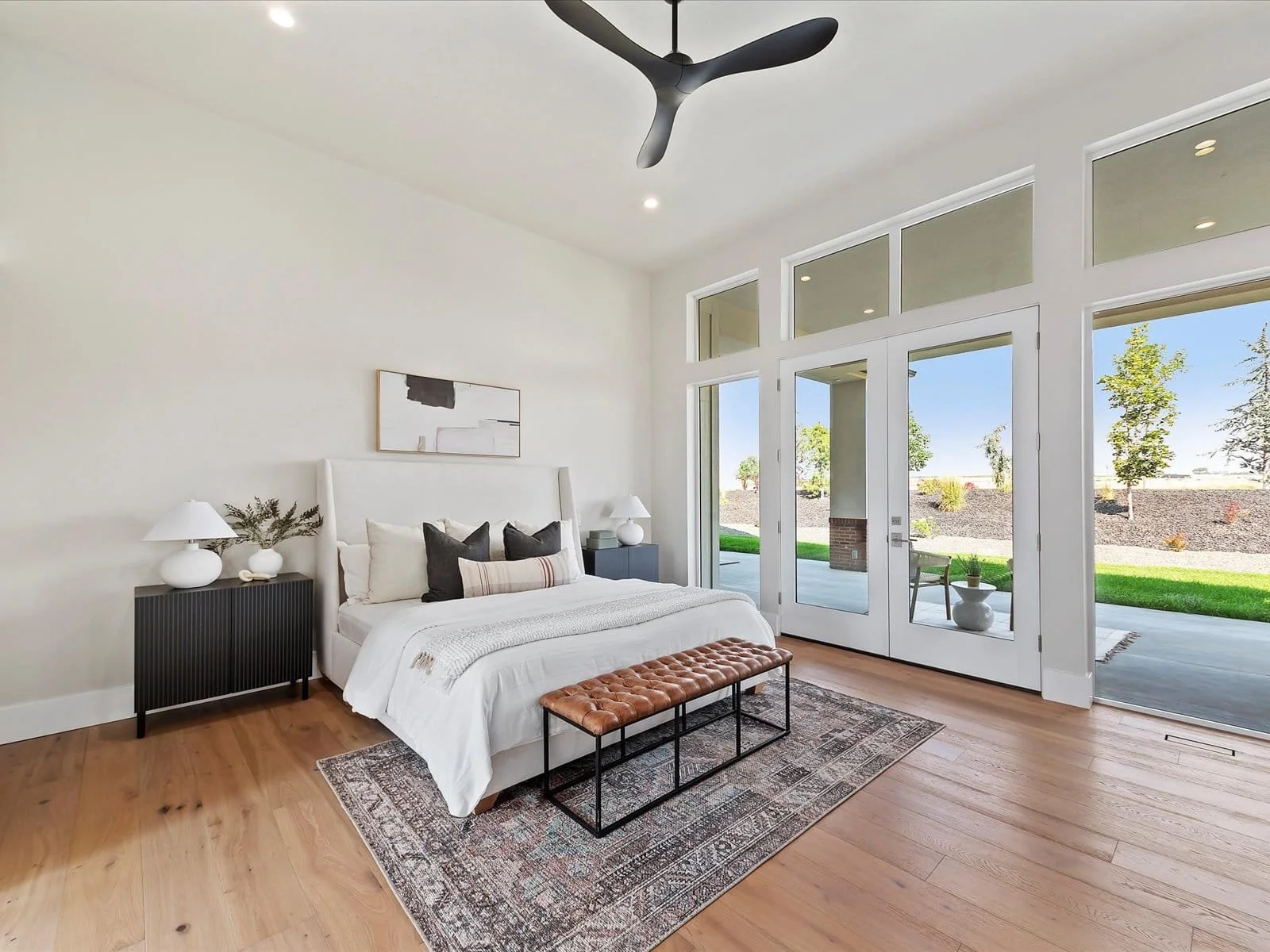 Eagle, Idaho Homes, LLC - Modern bedroom with large windows, bed, nightstands, and decorative elements.