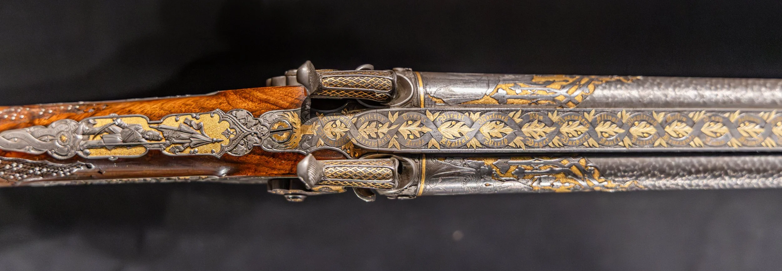 A top-down view of a double barrel percussion muzzleloader with intricate gold inlay and engraving.