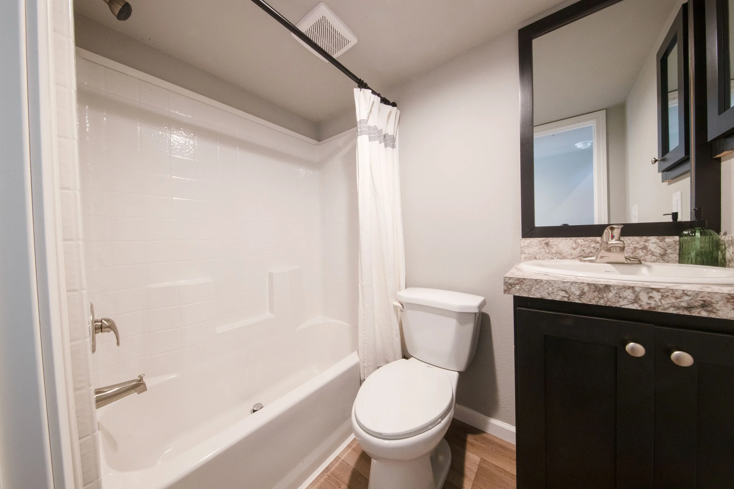 Snohomish Hemlock model bathroom with shower/tub combo, toilet, black cabinets, mirror trim, and medicine cabinet