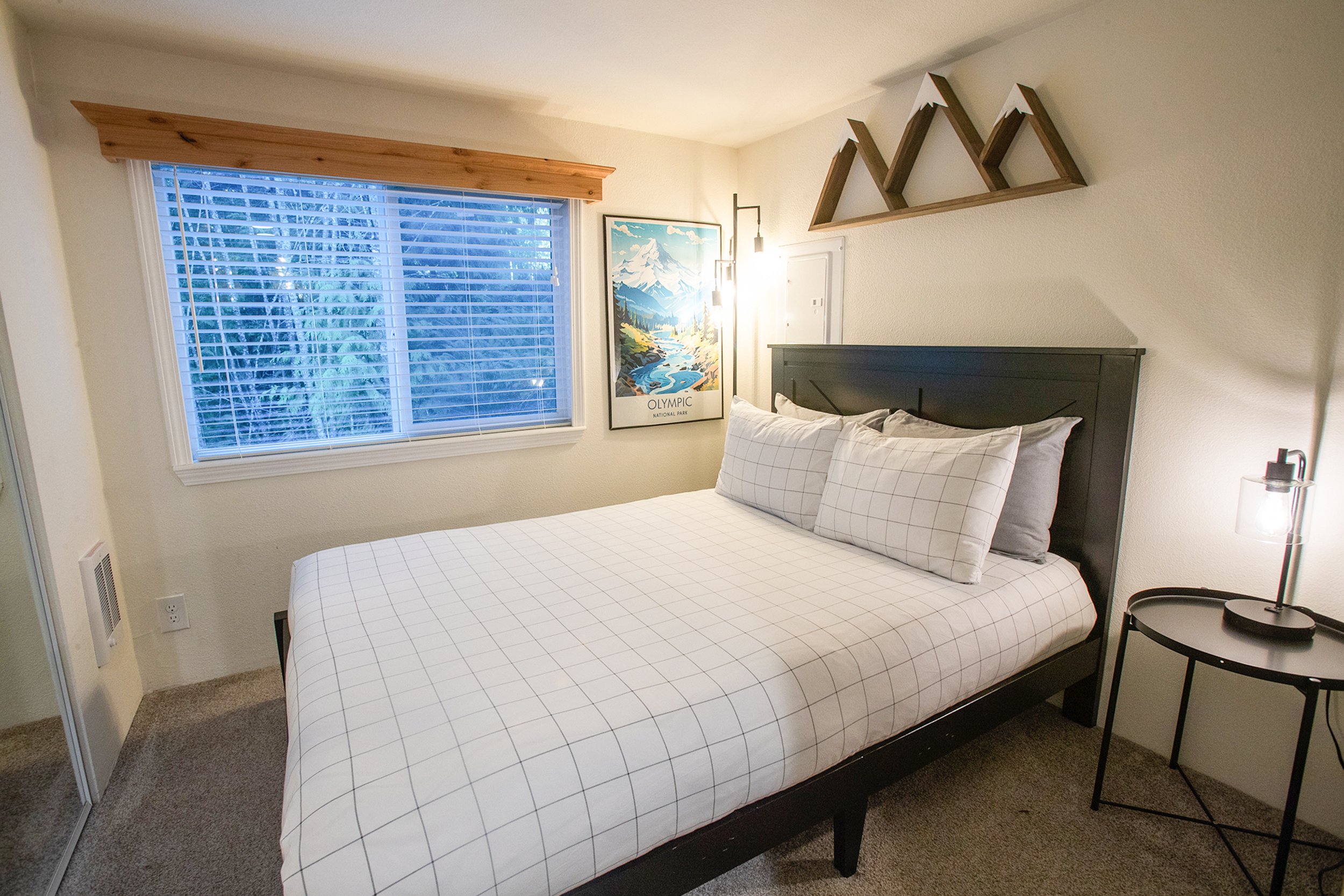 Tiny home bedroom fits a queen size bed, end tables, and floor lamp