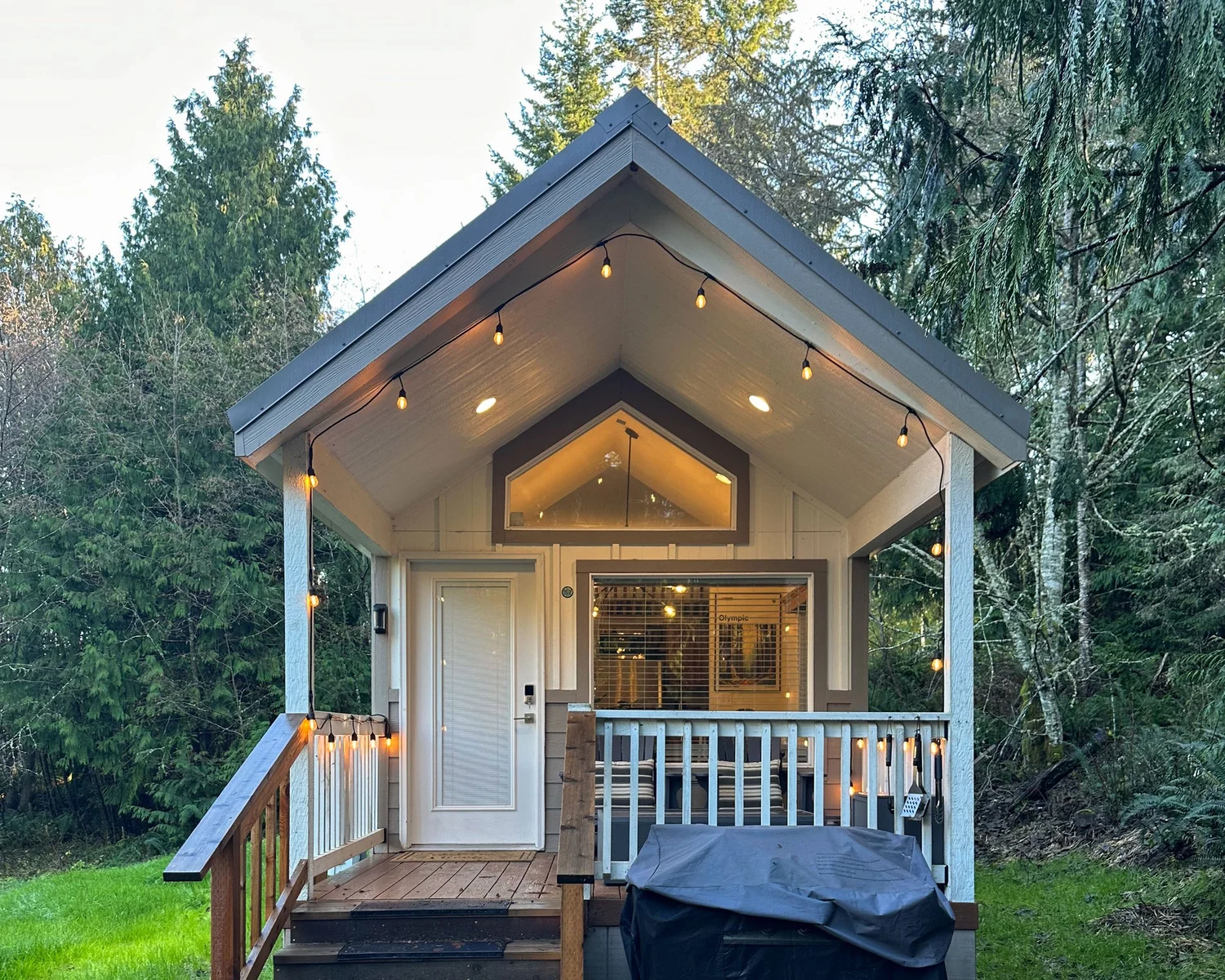 A tiny home with string lights and a glowing porch at dusk