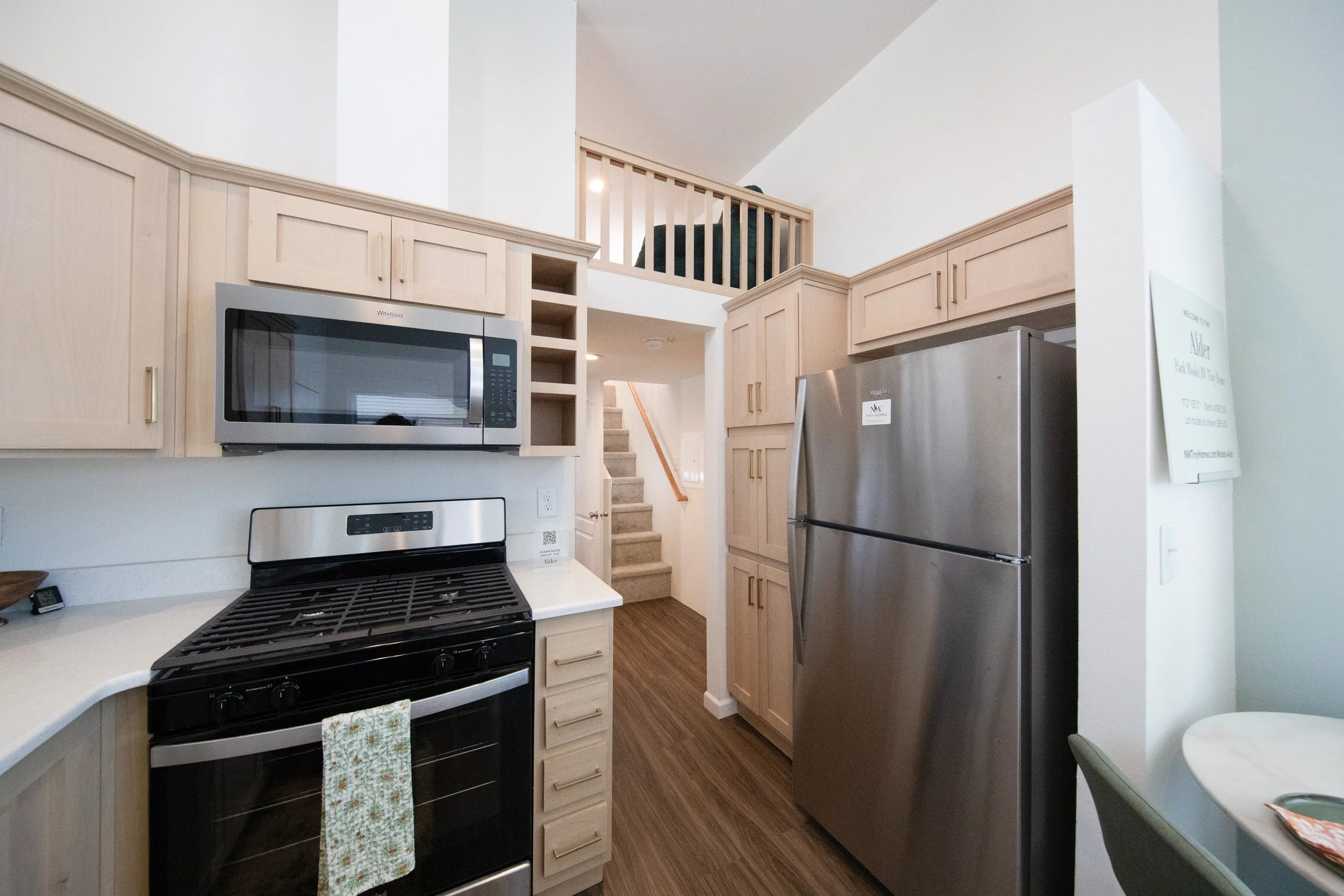 Portland Alder model kitchen with Snow Plank cabinets, gas range, above-range microwave, and fridge