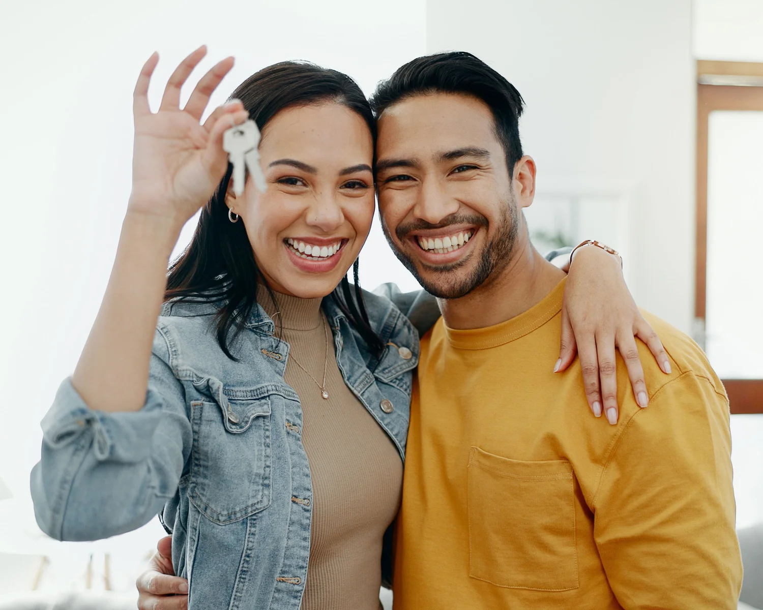 A couple holding up house keys, smiling