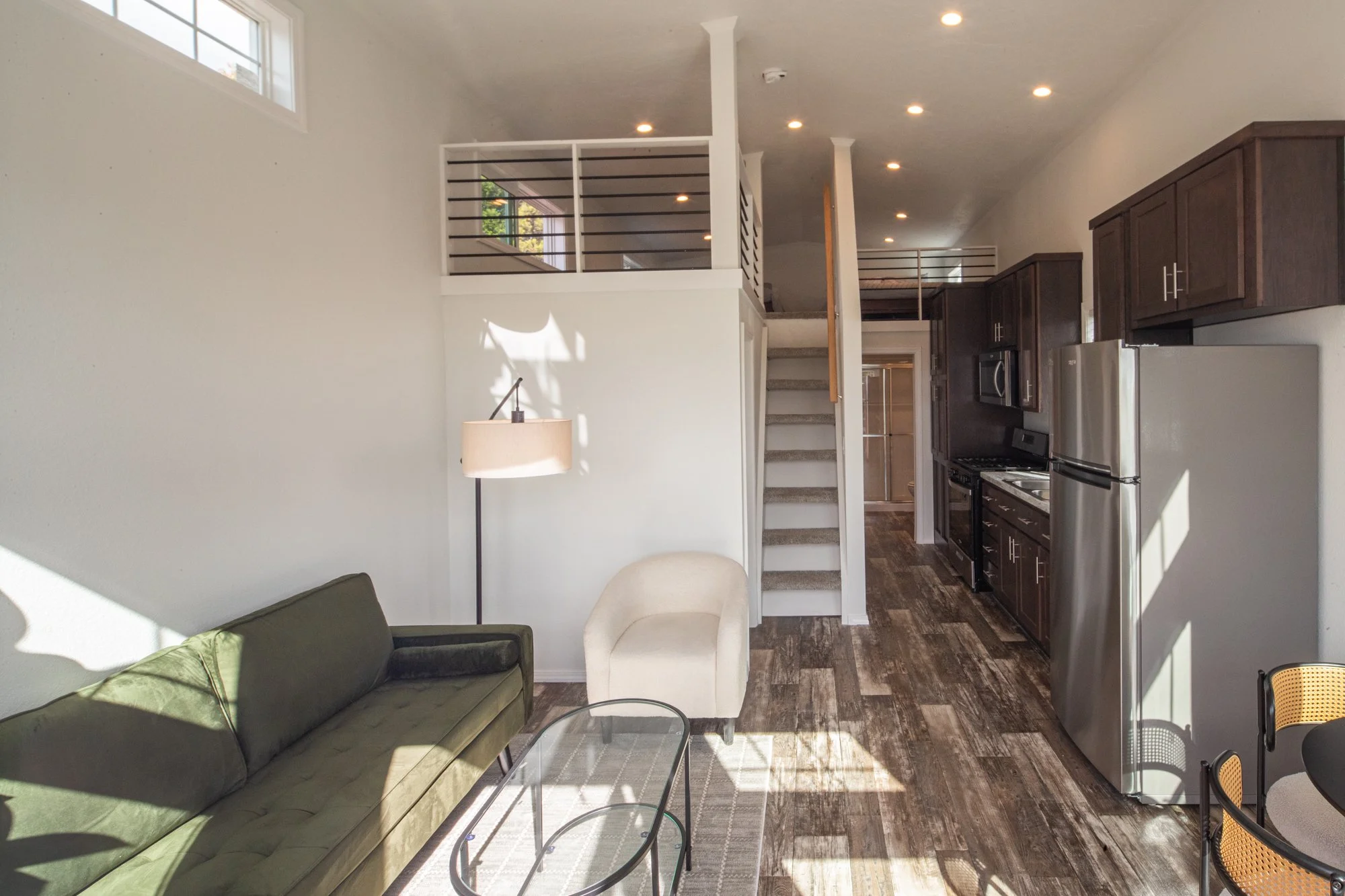 Interior of a tiny home, showing a living room, loft, and a small bunkroom