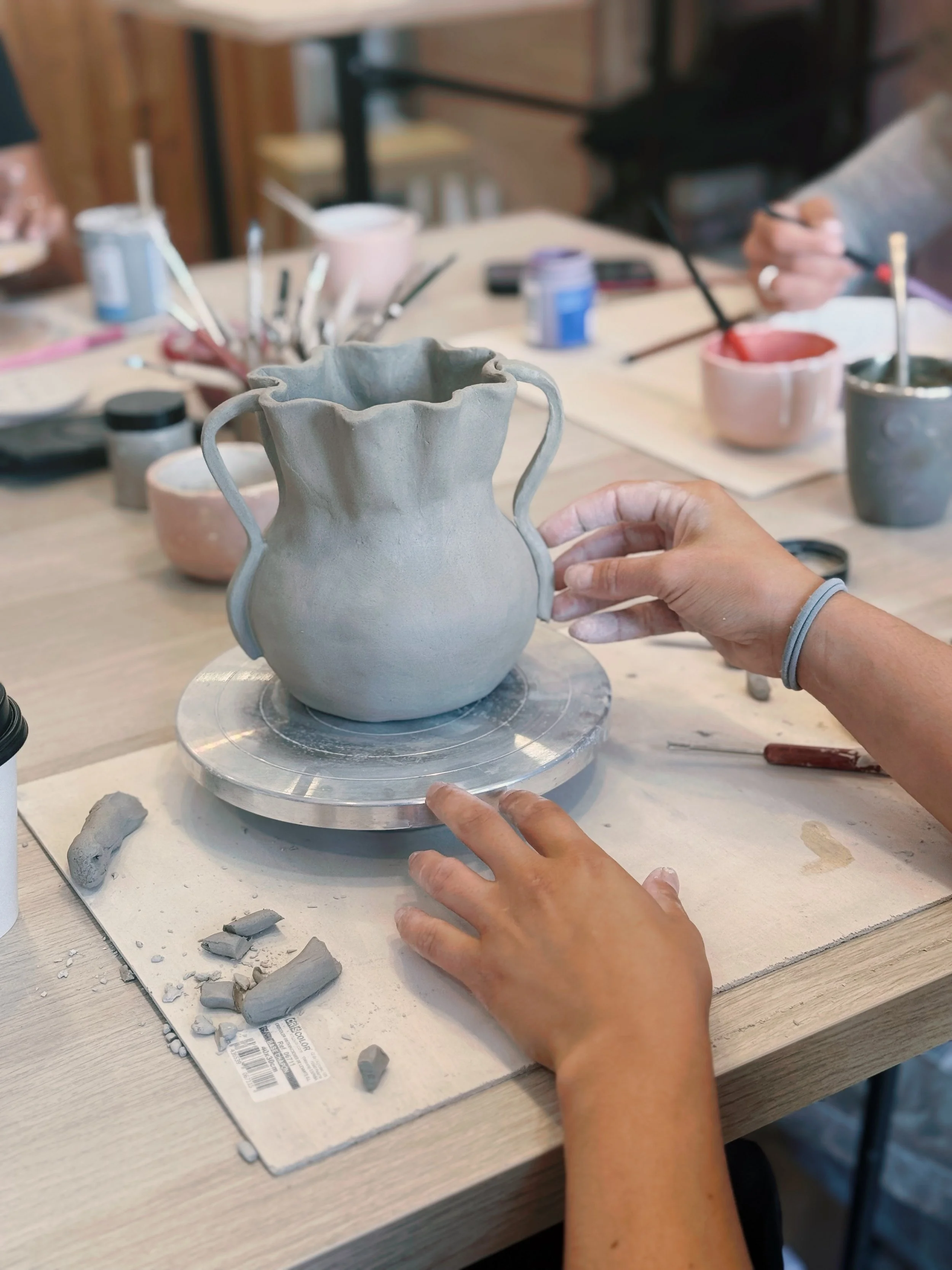 Persona trabajando en la creación de una cerámica en una rueda de alfarero en un taller.