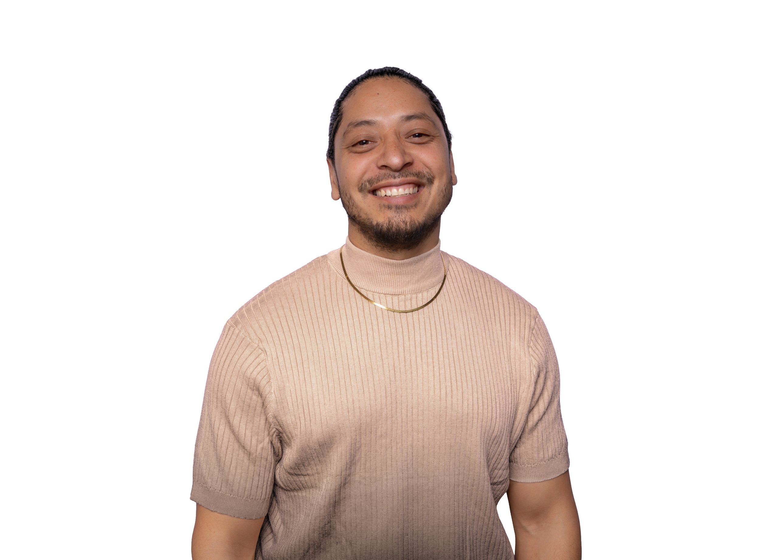 Smiling person wearing a beige ribbed shirt and a gold chain necklace against a white background.
