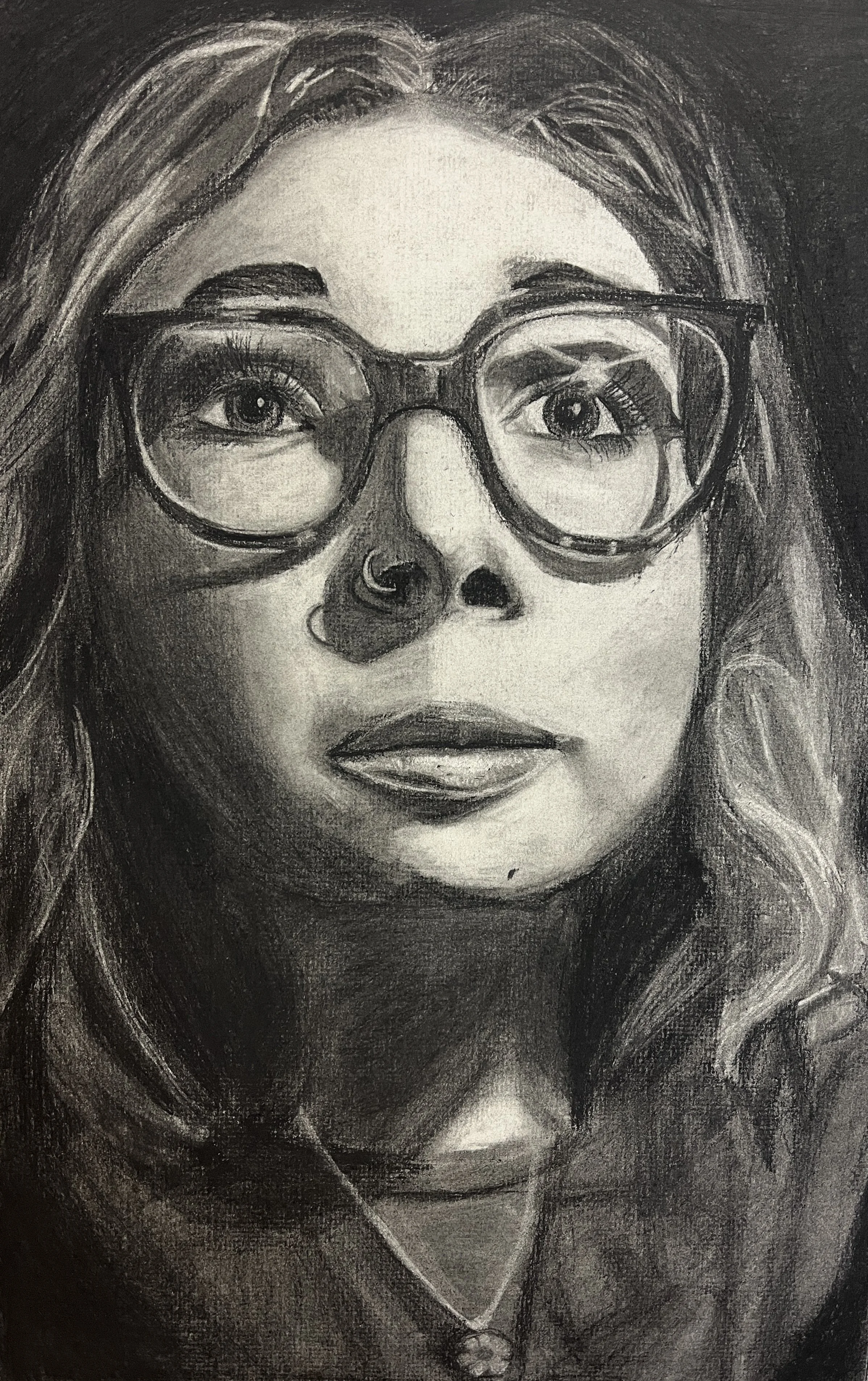 A grayscale portrait of a woman with wavy hair wearing glasses, a nose ring, and a necklace.