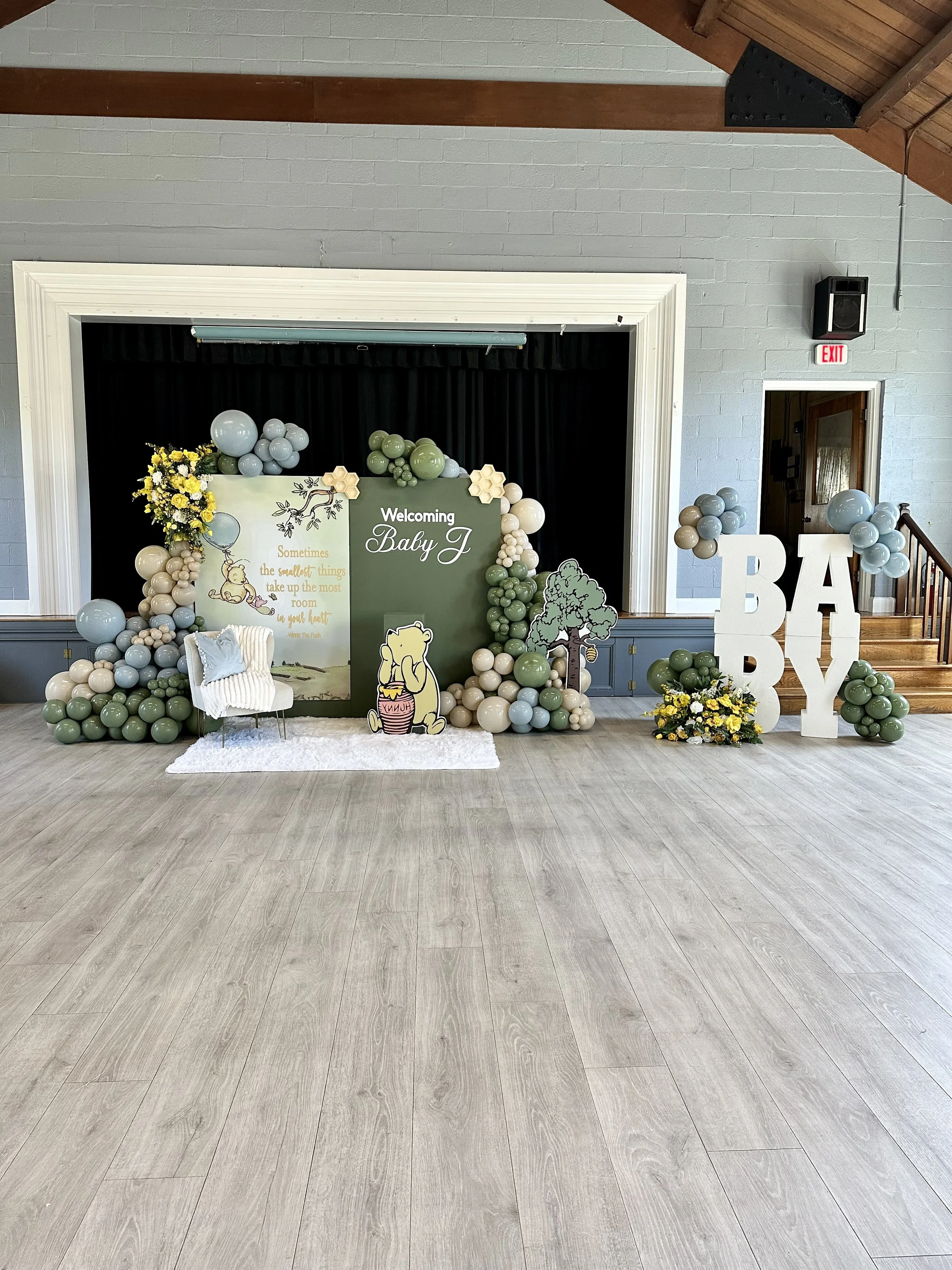Decorative backdrop for a welcome baby event with balloons, flowers, and large letters spelling 'BABY'.