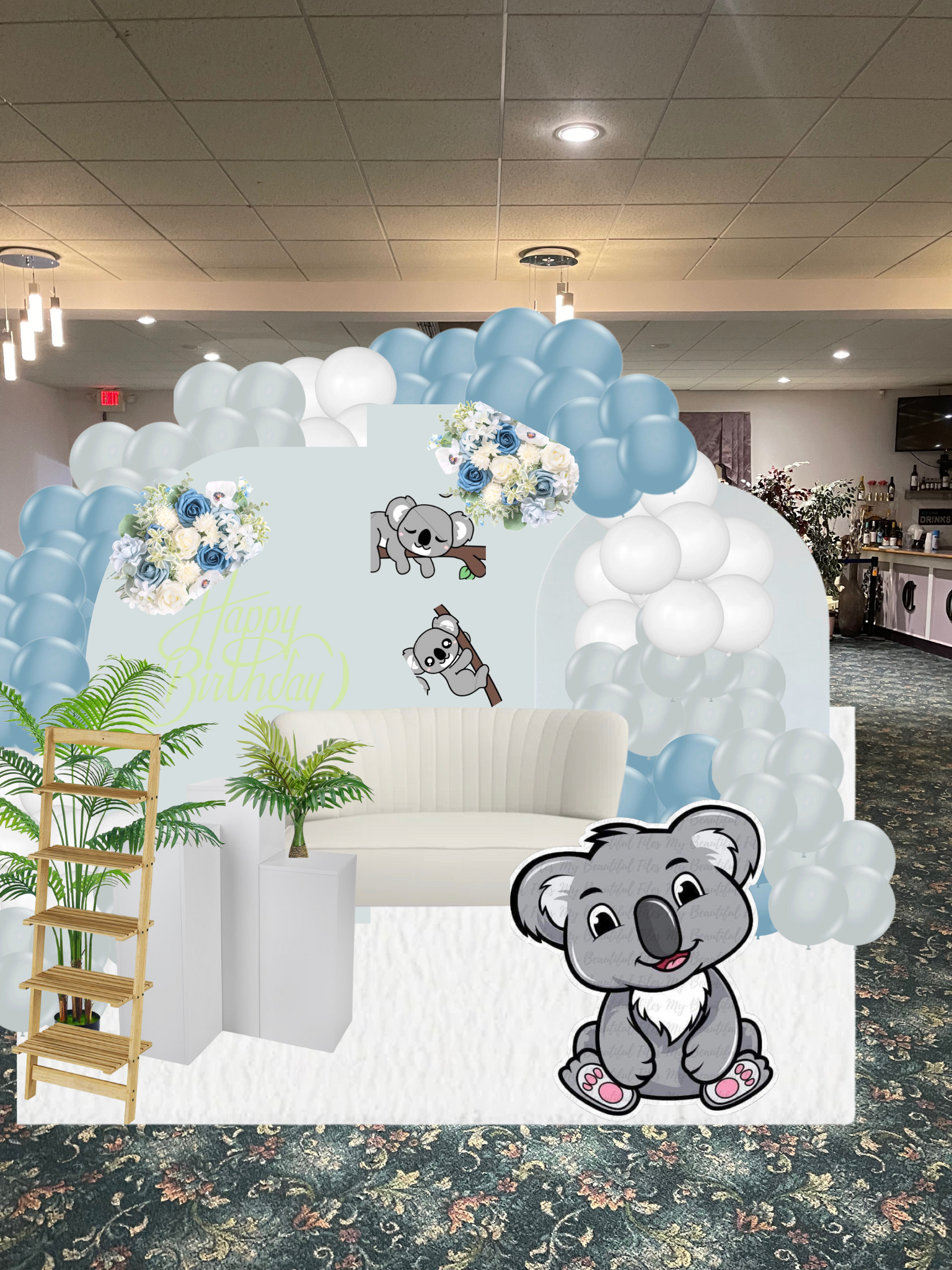 Decorated birthday celebration area with white and blue balloons, koala-themed cardboard cutouts, a white bench, and potted plants, set on a patterned carpet in an indoor space.