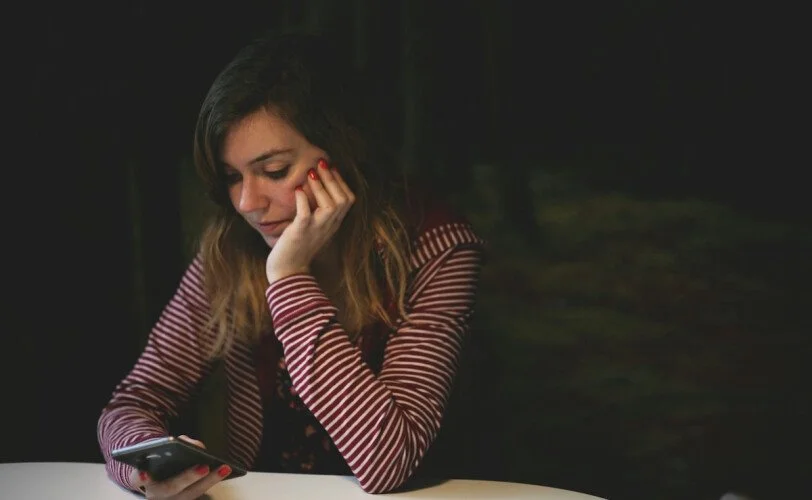 Woman looking at her phone while leaning on her hand