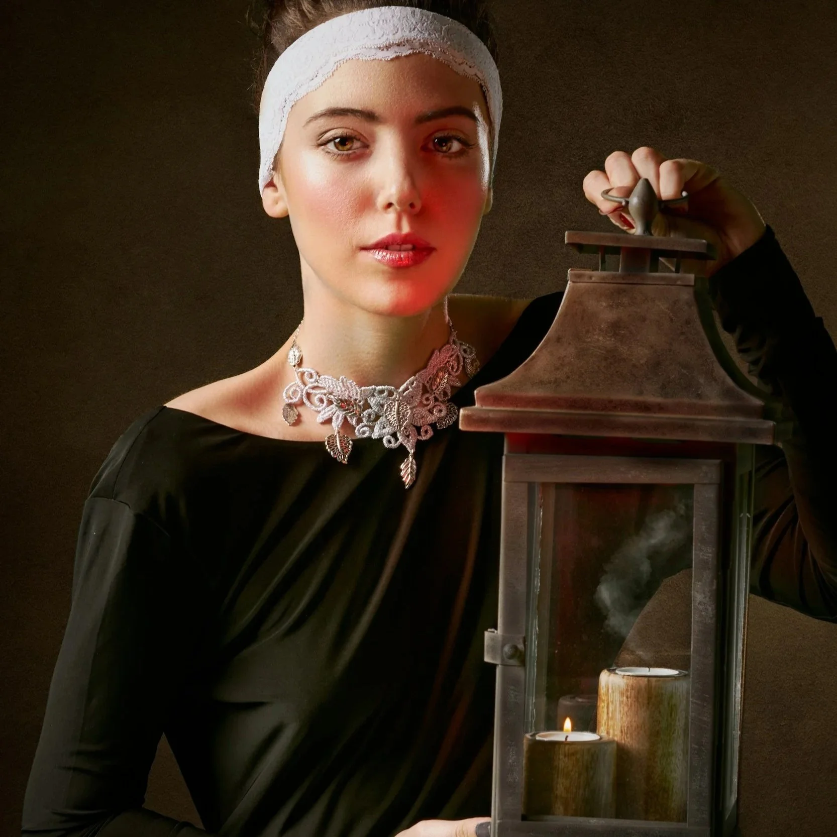 Woman standing with candles in a lamp.