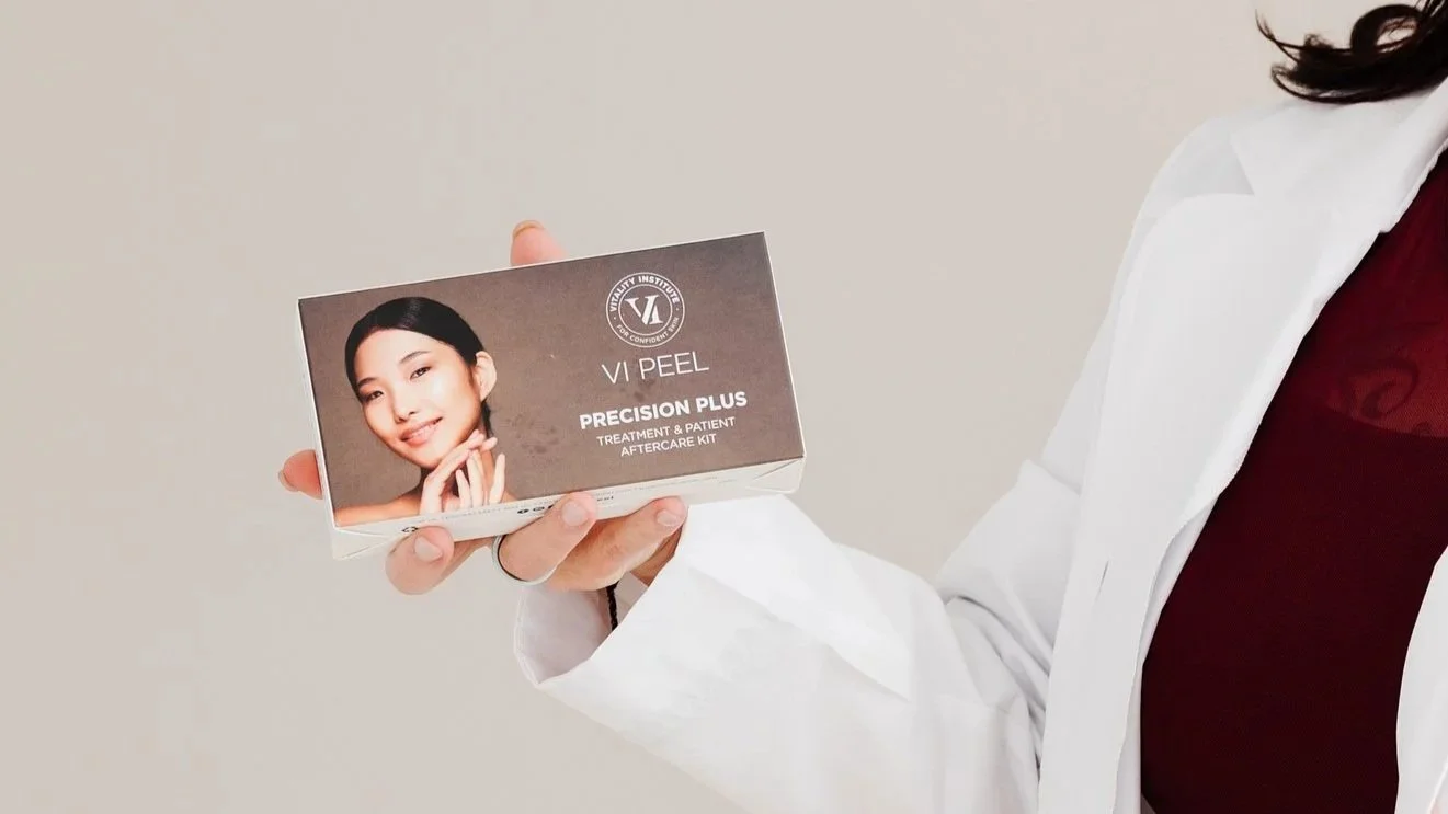 Person holding a box of VI Peel skincare product, with a woman’s face on the packaging, against a plain background.