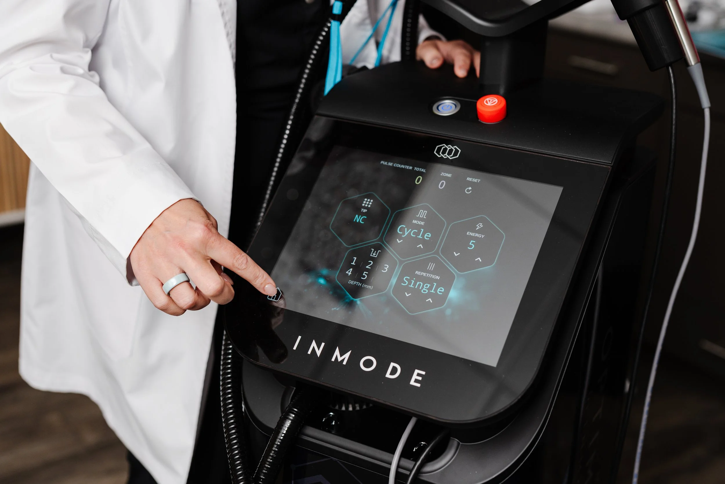 Close-up of a medical professional operating a touchscreen control panel on a medical device with buttons and symbols, indicating a healthcare or medical setting.