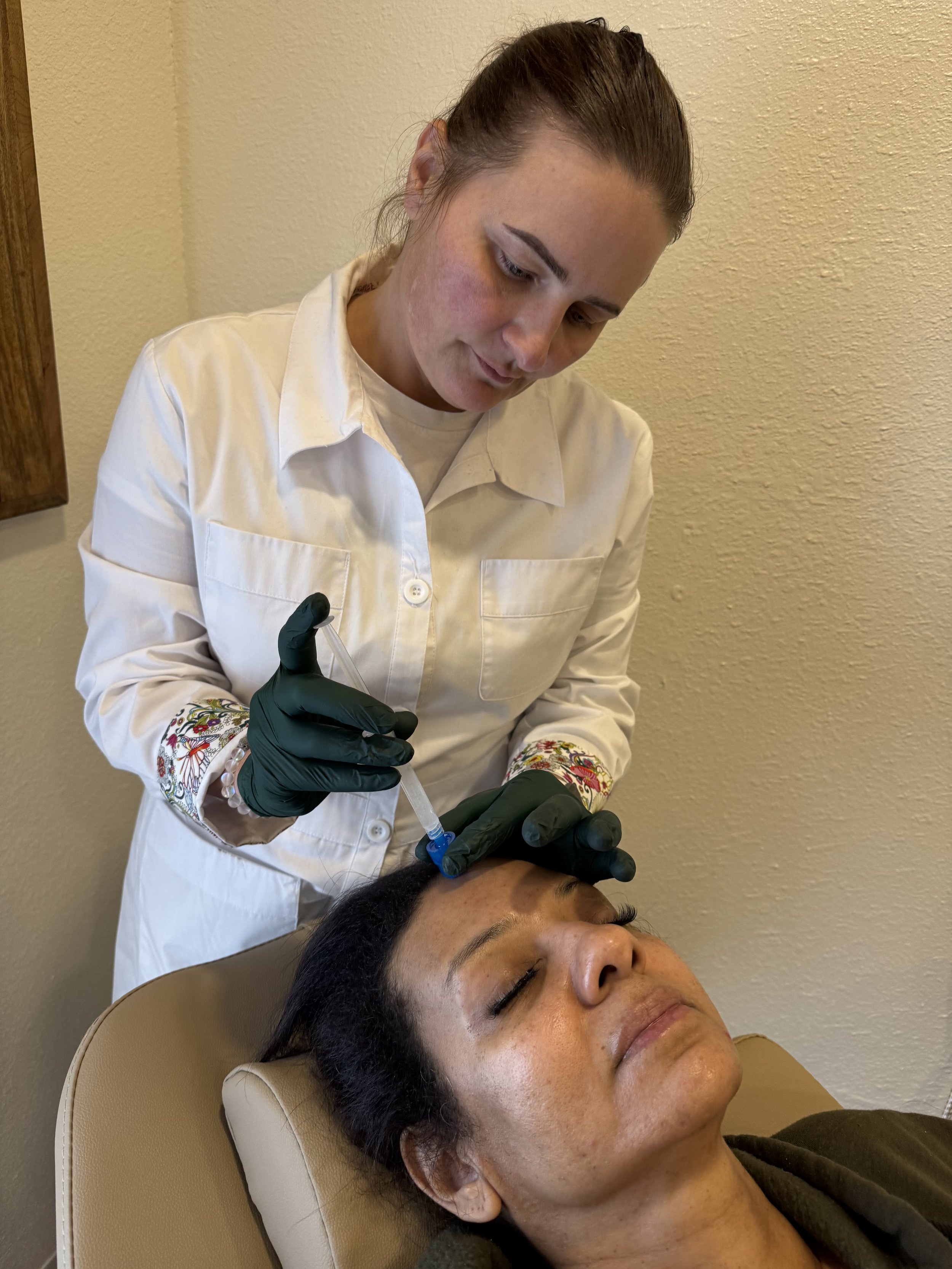 Aesthetician performing facial treatment on a reclining woman