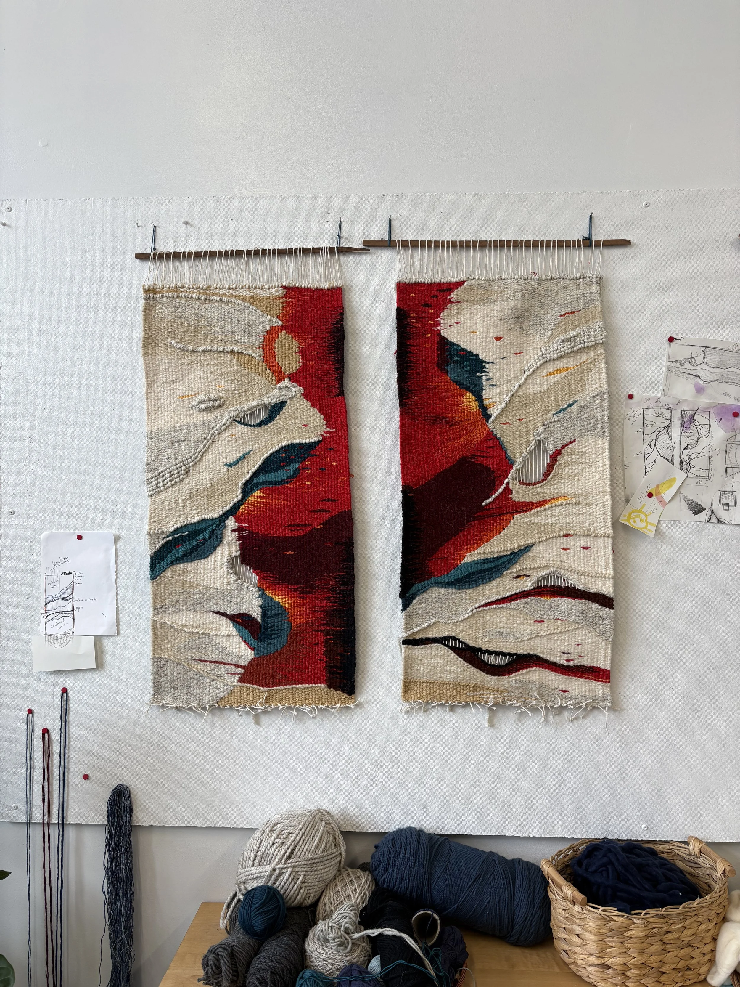 Two woven tapestries hanging on a wall, featuring abstract colorful designs with shades of red, beige, teal, and black.