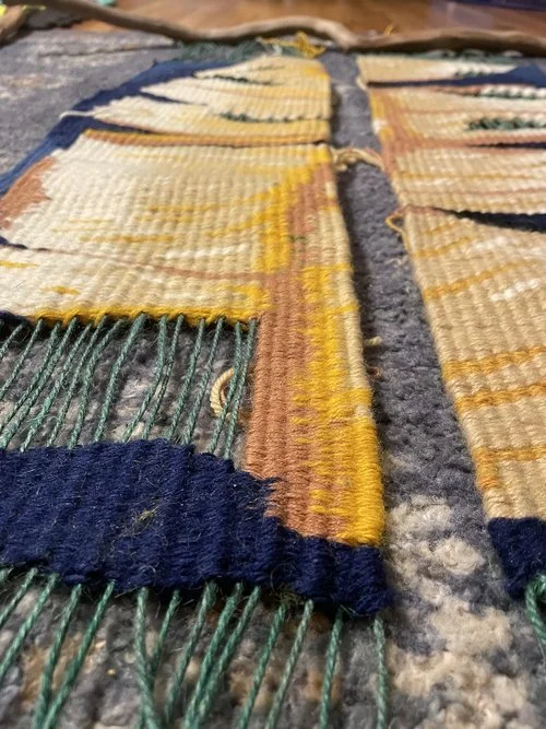 Close-up of a partially woven textile or rug with some sections completed and others still in progress on a loom.