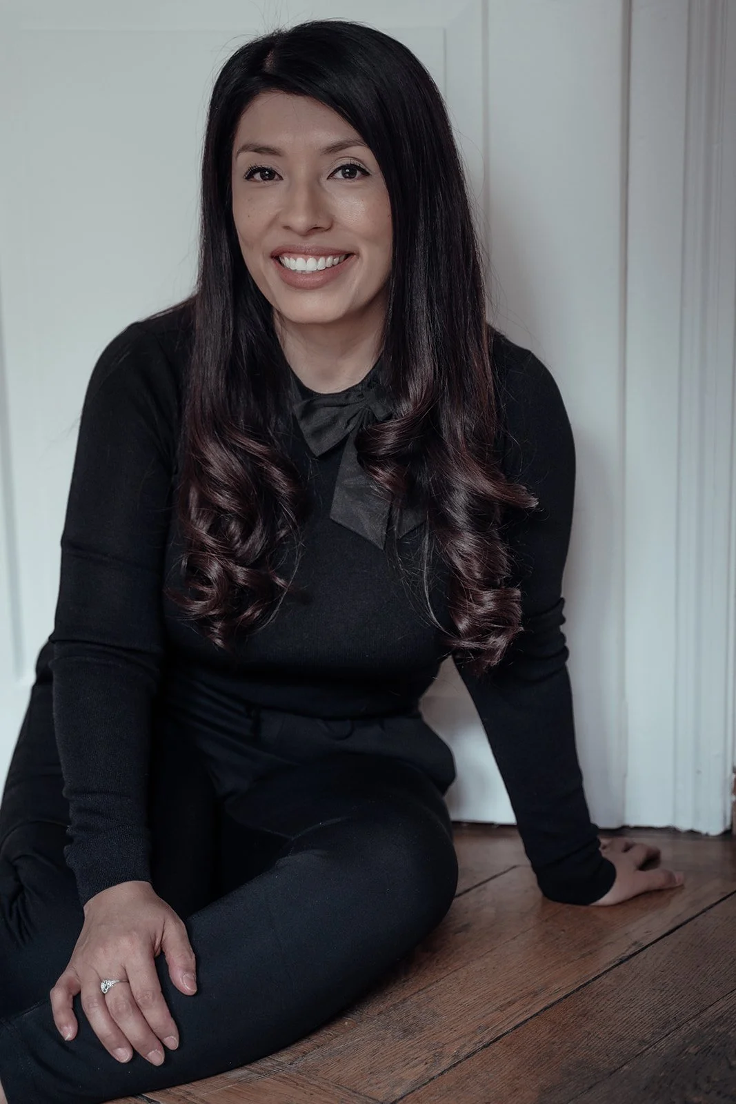 Tanja Paola Hasbi sitzt lächelnd in einem hellen Raum.