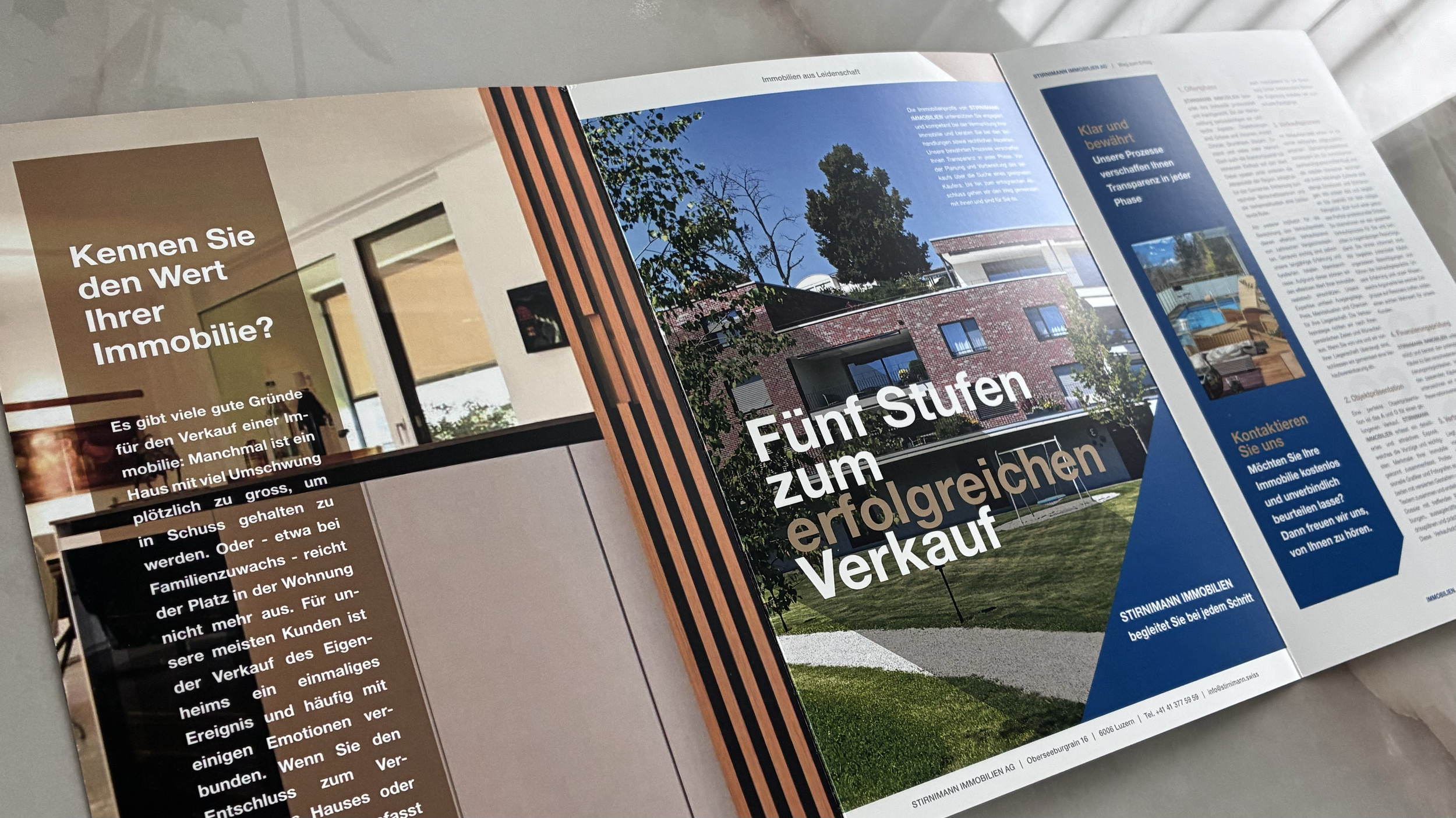 Offener Immobilien-Prospekt mit einem mehrstöckigen roten Backsteinhaus, umgeben von grünen Bäumen und einem Garten, mit dem Titel ‚Fünf Stufen zum erfolgreichen Verkauf‘ und blauer Schrift auf der rechten Seite.