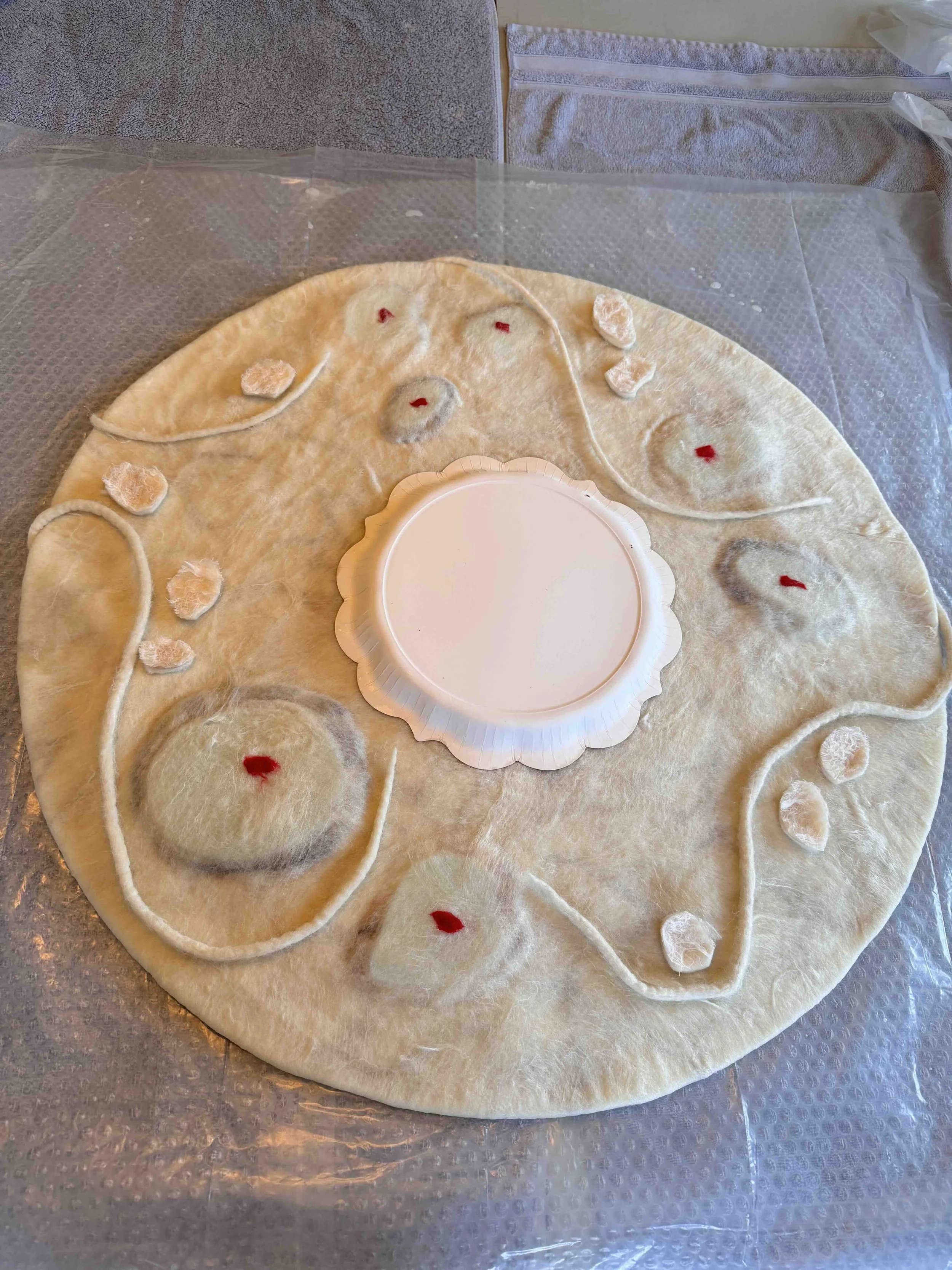 Covering craters and cords with layers of wool, marking the craters with red so I can find them later to cut them open. The paperplate is to estimate where the hole will be. 