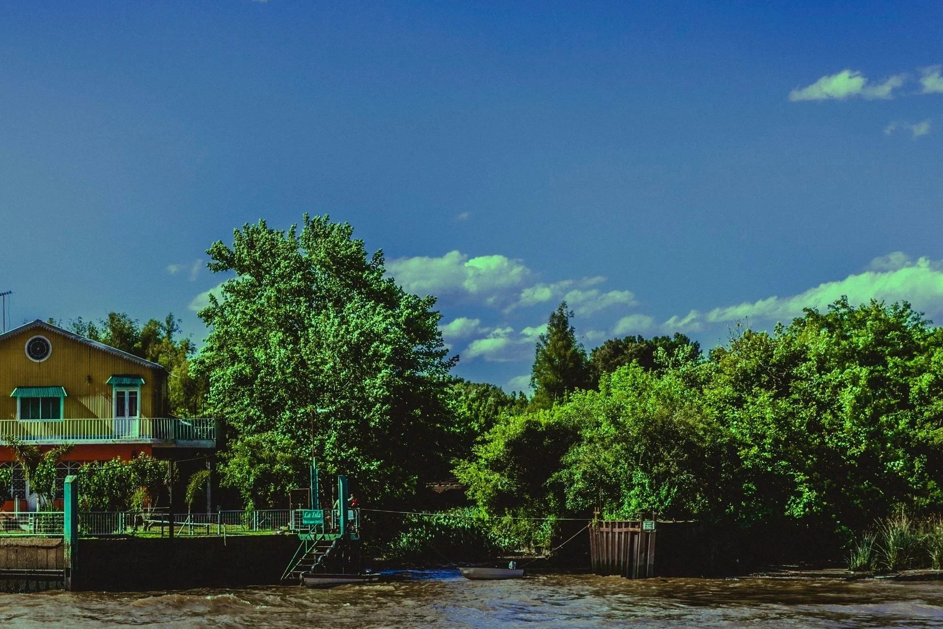 Río marrón en primer plano con una casa al fondo bajo un cielo azul, representando el proceso de salir de la depresión hacia un estado más claro y equilibrado.