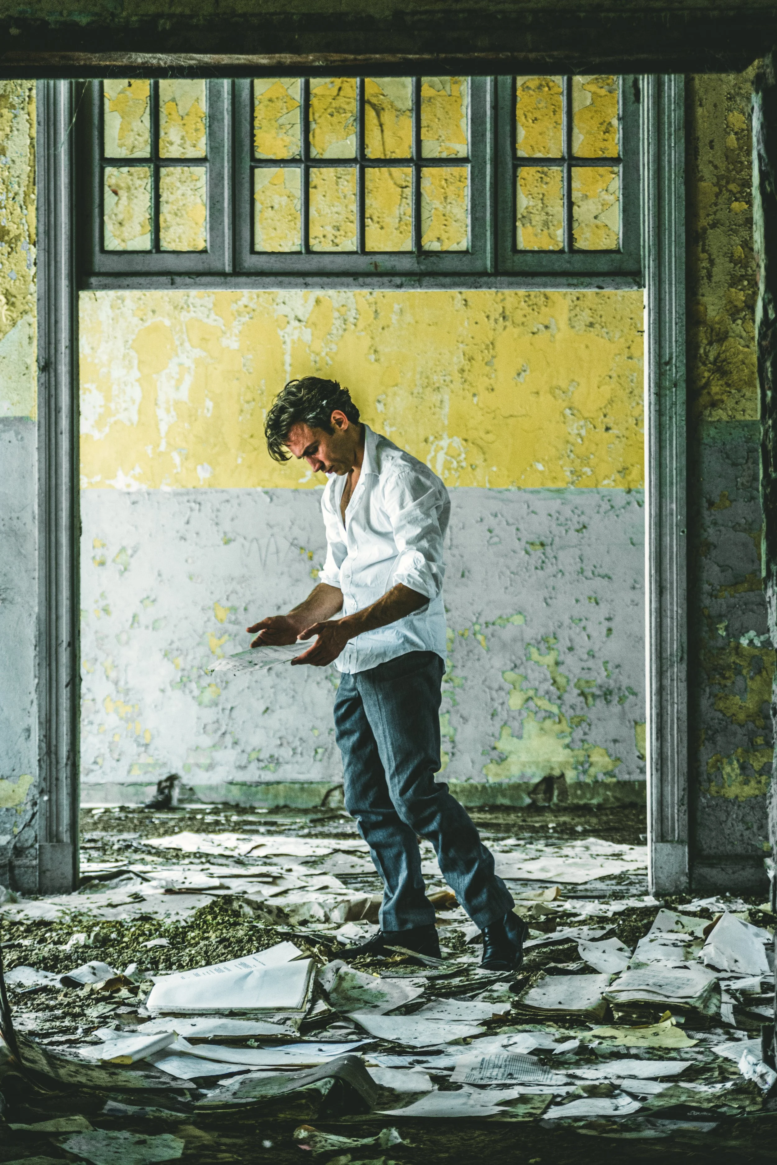 Figura masculina en un entorno abandonado mirando sus manos con desánimo, representando el peso emocional del trauma y la necesidad de trabajo terapéutico.