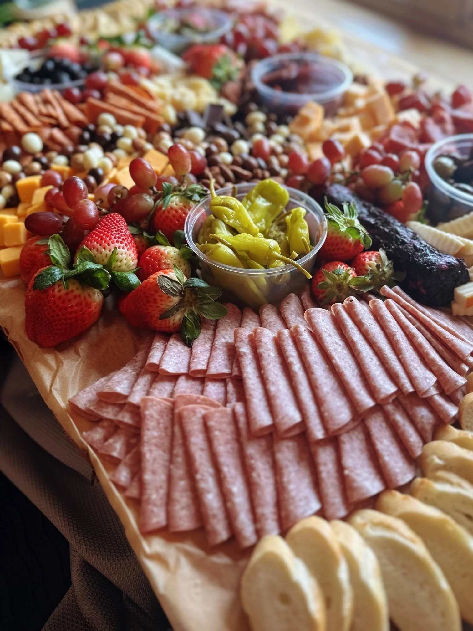 Close up shot of a charcuterie tray filled wwith meats, cheeses, grapes, strawberries, and peppers