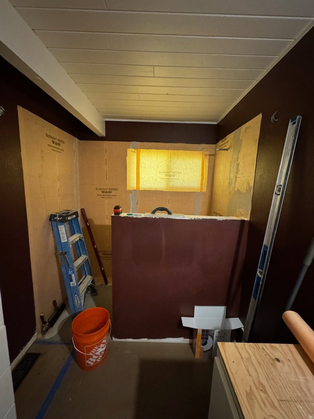 Bathroom under renovation with a partially built wall, tools, and construction materials.