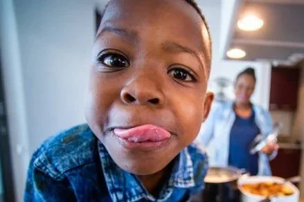 Two women taking a selfie outdoors near a river, smiling and making funny faces.