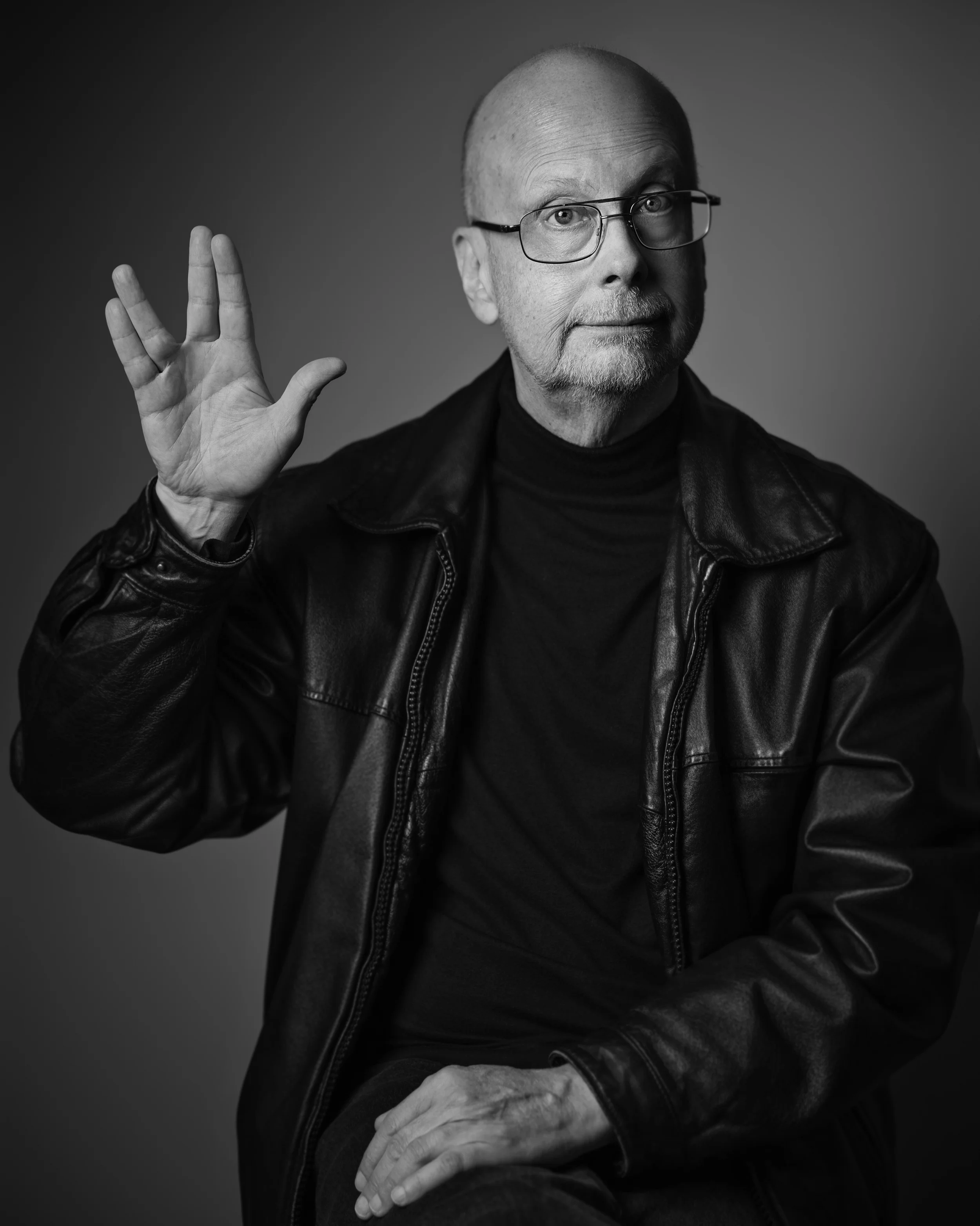 Black and white portrait of Robert J. Sawyer, Hugo and Nebula Award winning Sci-fi author, making the Vulcan salute.