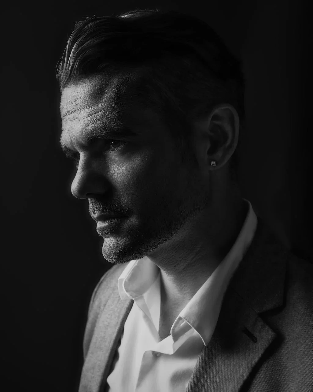 Moody close up editorial portrait of Frankie Guerreiro, aka: Sylvon Music, wearing a blazer and white dress shirt.