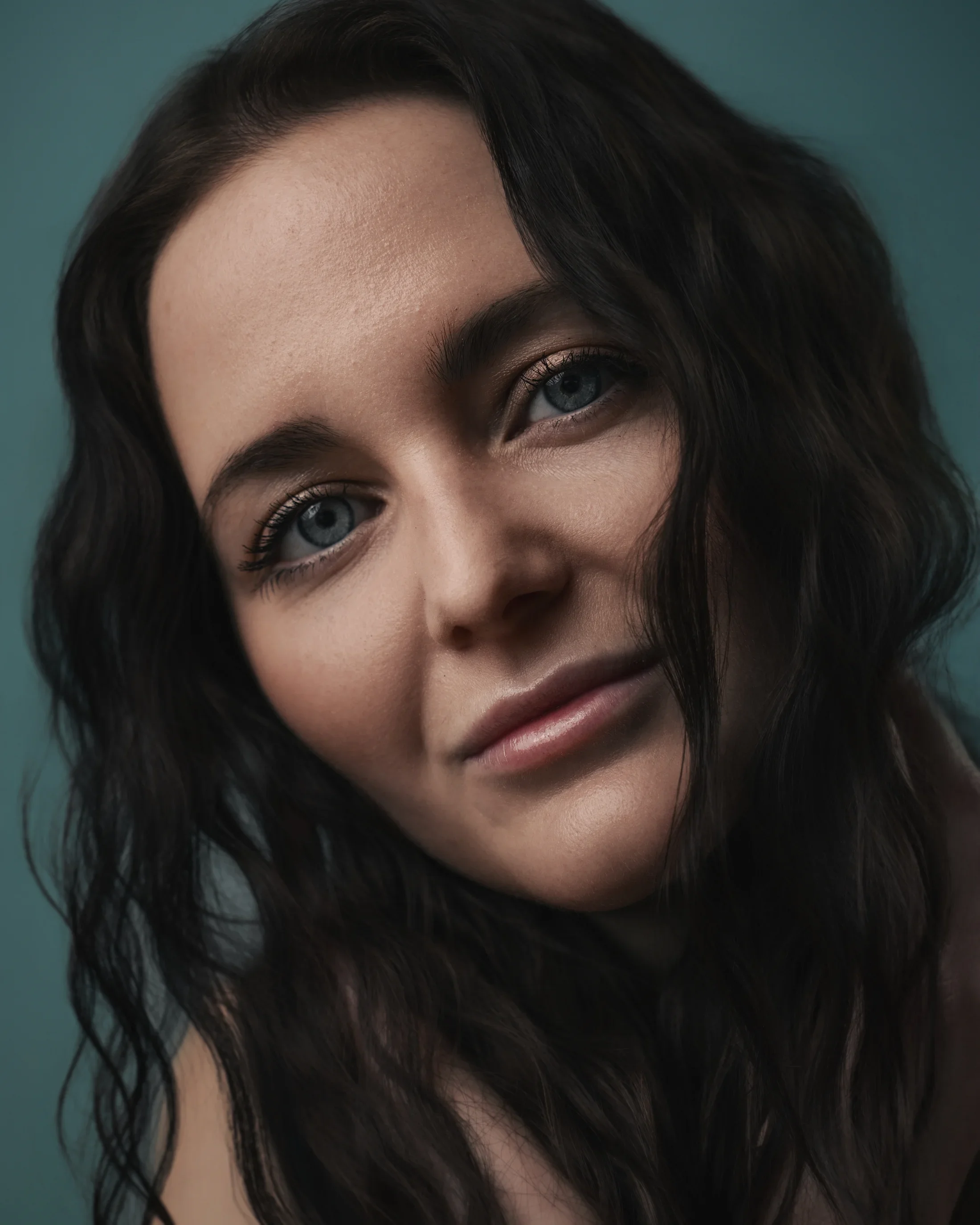 Portrait of a woman with long wavy hair and large blue eyes, looking directly at the camera.