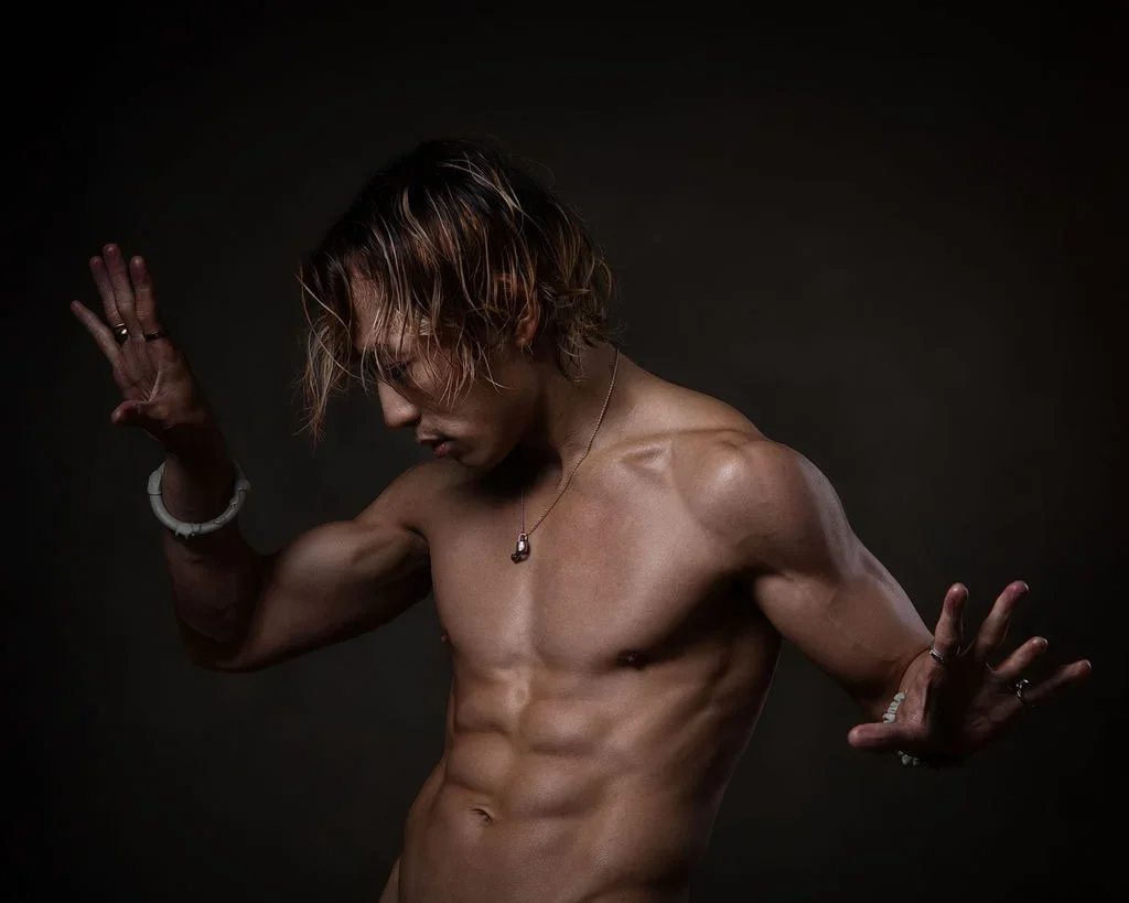 Dramatic editorial portrait of a shirtless Grei Lance in a dramatic dance pose, revealing his well-defined musculature.