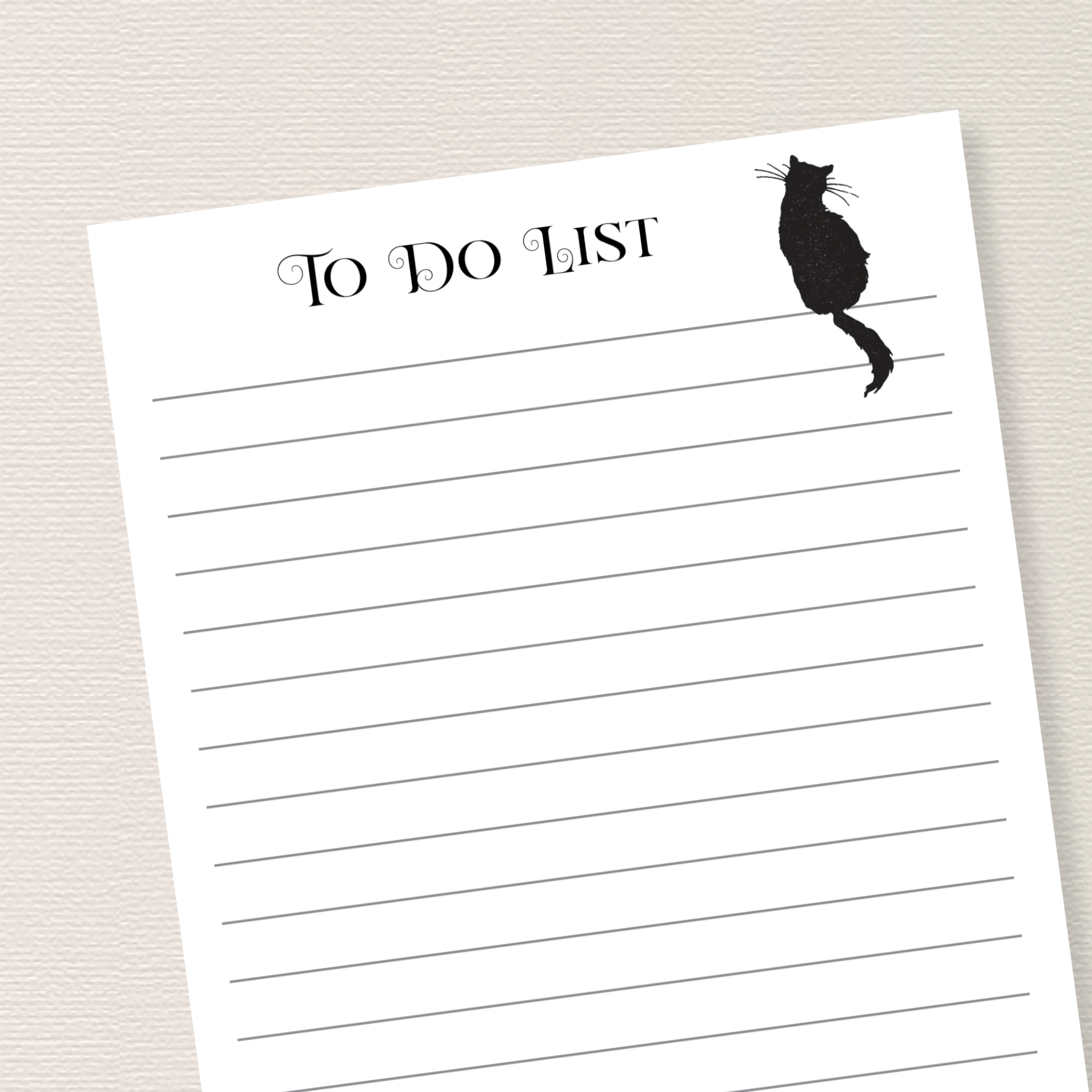 Close up of a lined notepad with black cat sitting on the top line. Text on top of notepad reads "To Do List".