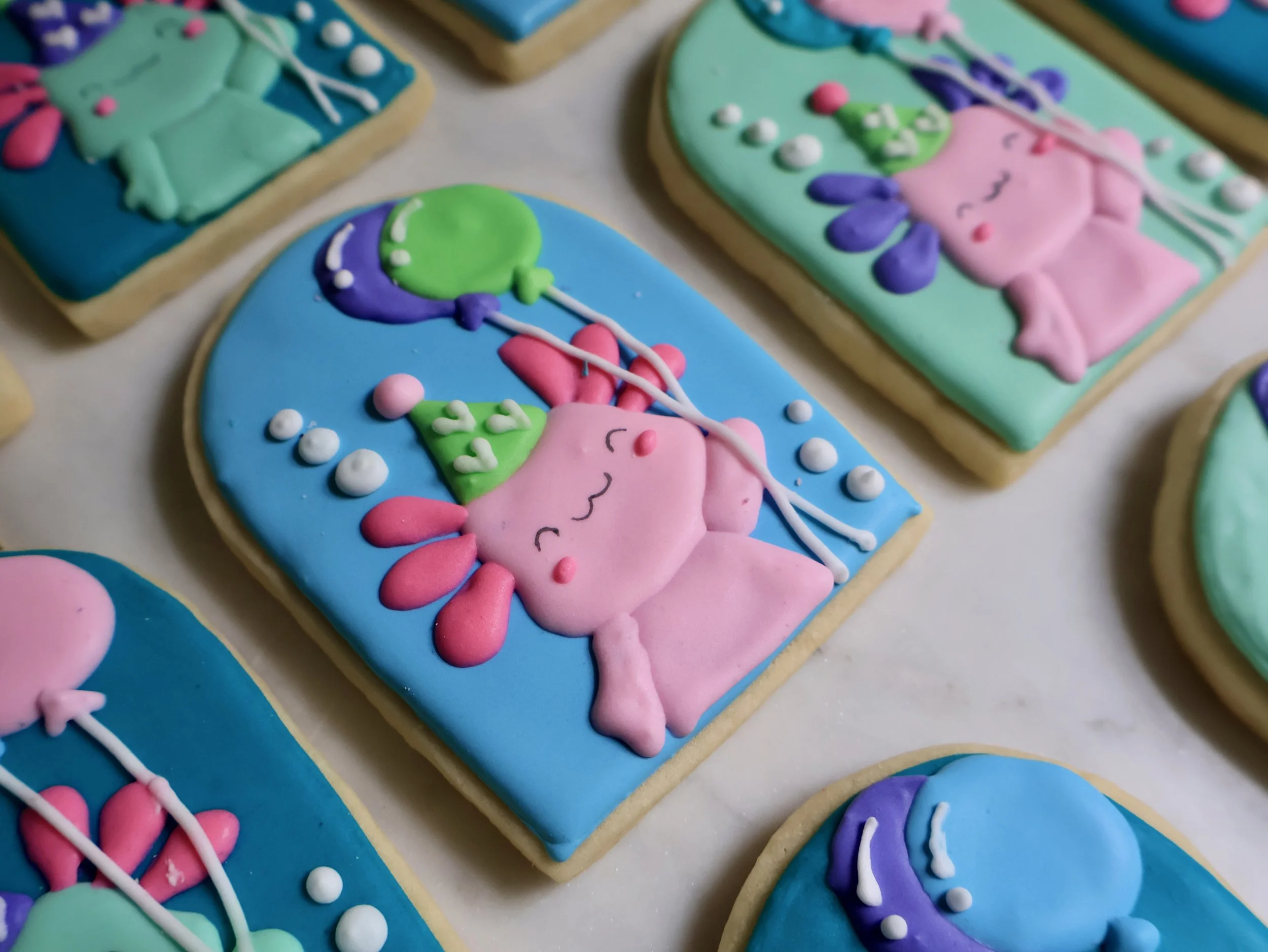 Colorful decorated cookies with pink unicorns, balloons, and pastel backgrounds.
