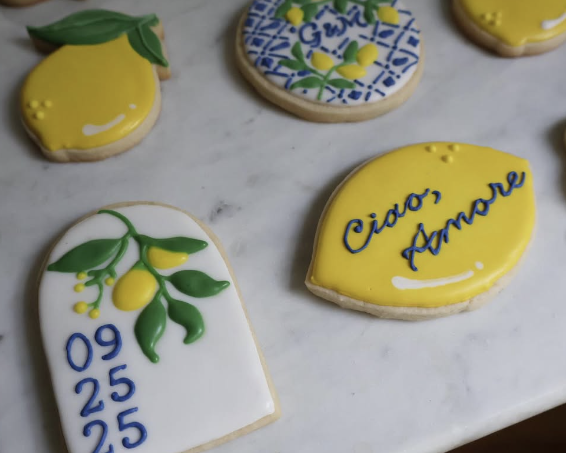 Decorative cookies with lemon, olive branch, and text in Italian that reads 'Ciao, Amore' on a white surface.