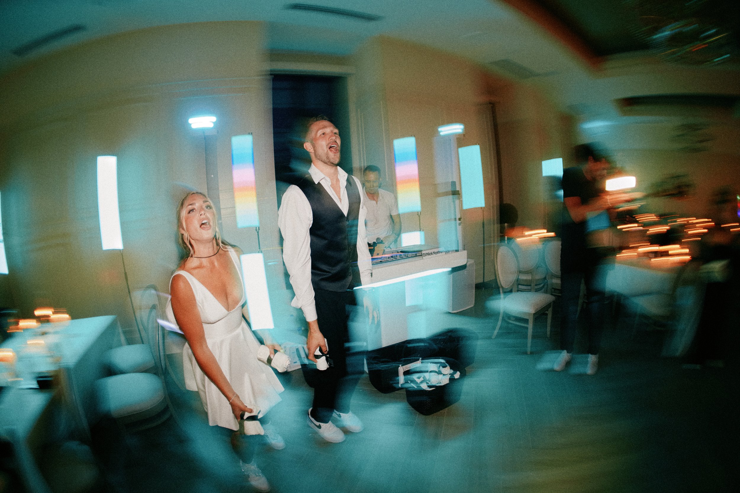 People singing at a karaoke event with colorful lighting in the background.