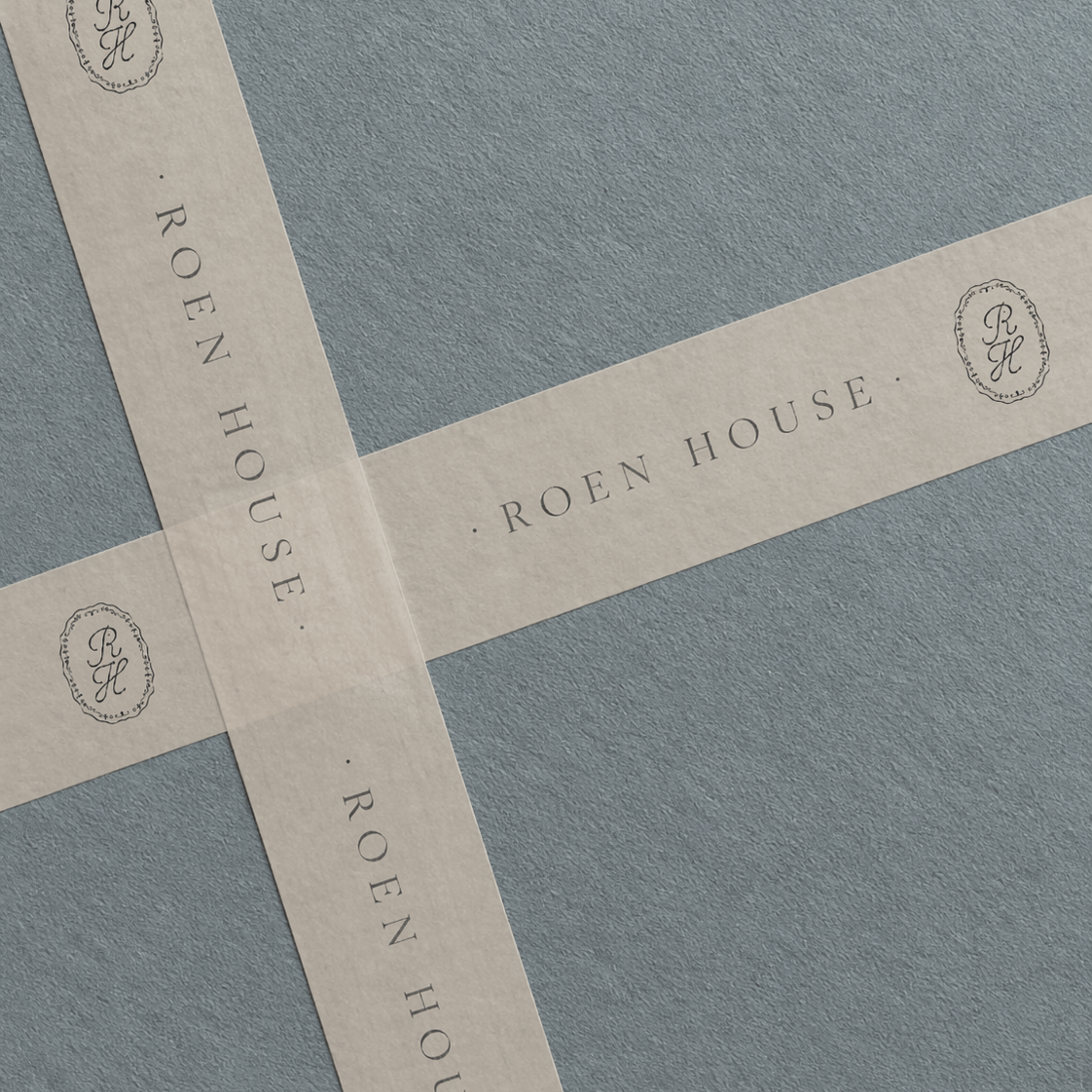 Close-up of several pieces of paper with elegant printed text and a decorative logo, laying on a textured gray surface.