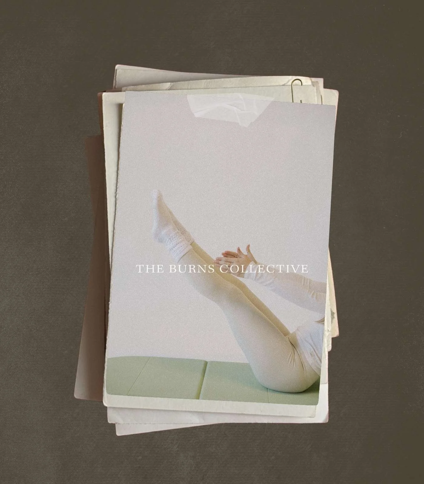 A white box containing a music album cover for "The Burns Collective" featuring a person lying down, wearing white clothing and white boots, with their legs crossed and hands extended toward the floor, on a plain surface.