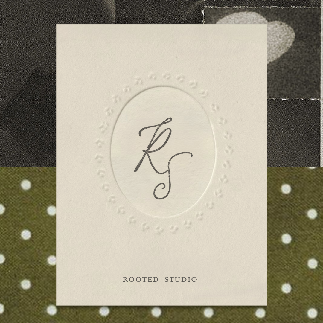 Close-up of an embossed logo with the initials 'RS' and the text 'ROOTED STUDIO' on a textured white card, against a background of patterned fabric with polka dots and different textures.