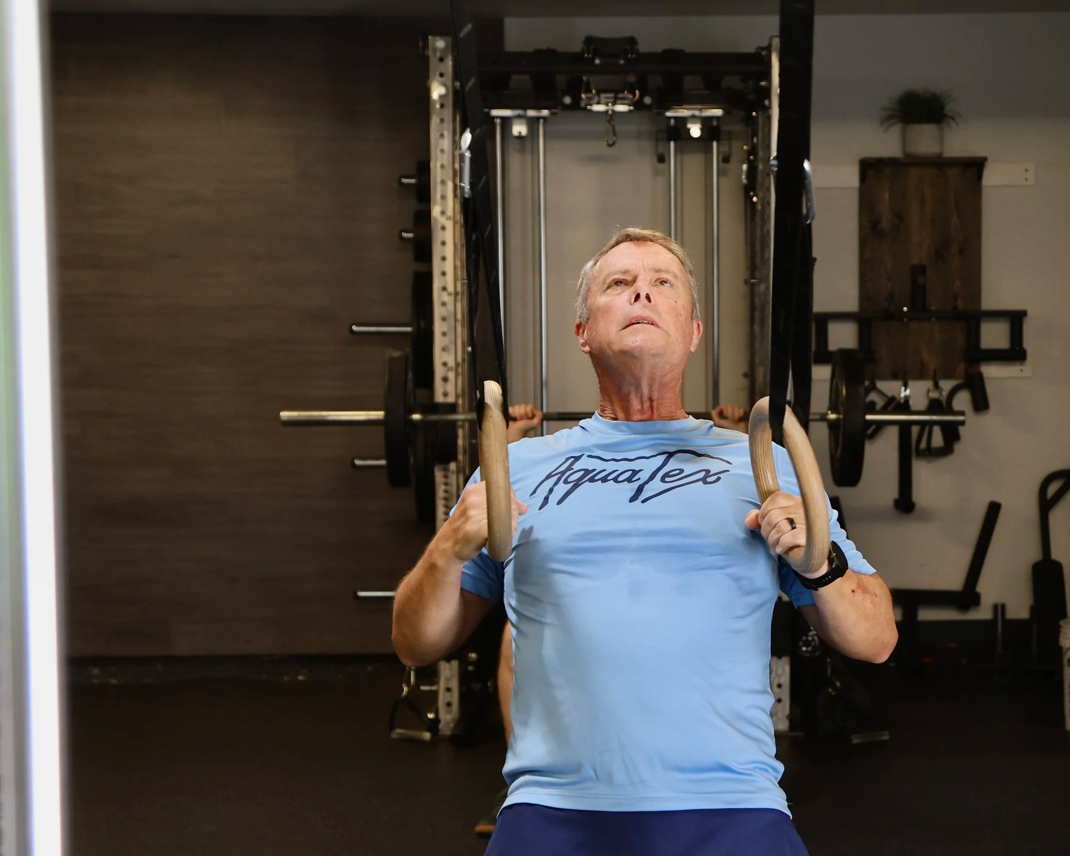 Opex round rock client using ring rows in the gym.