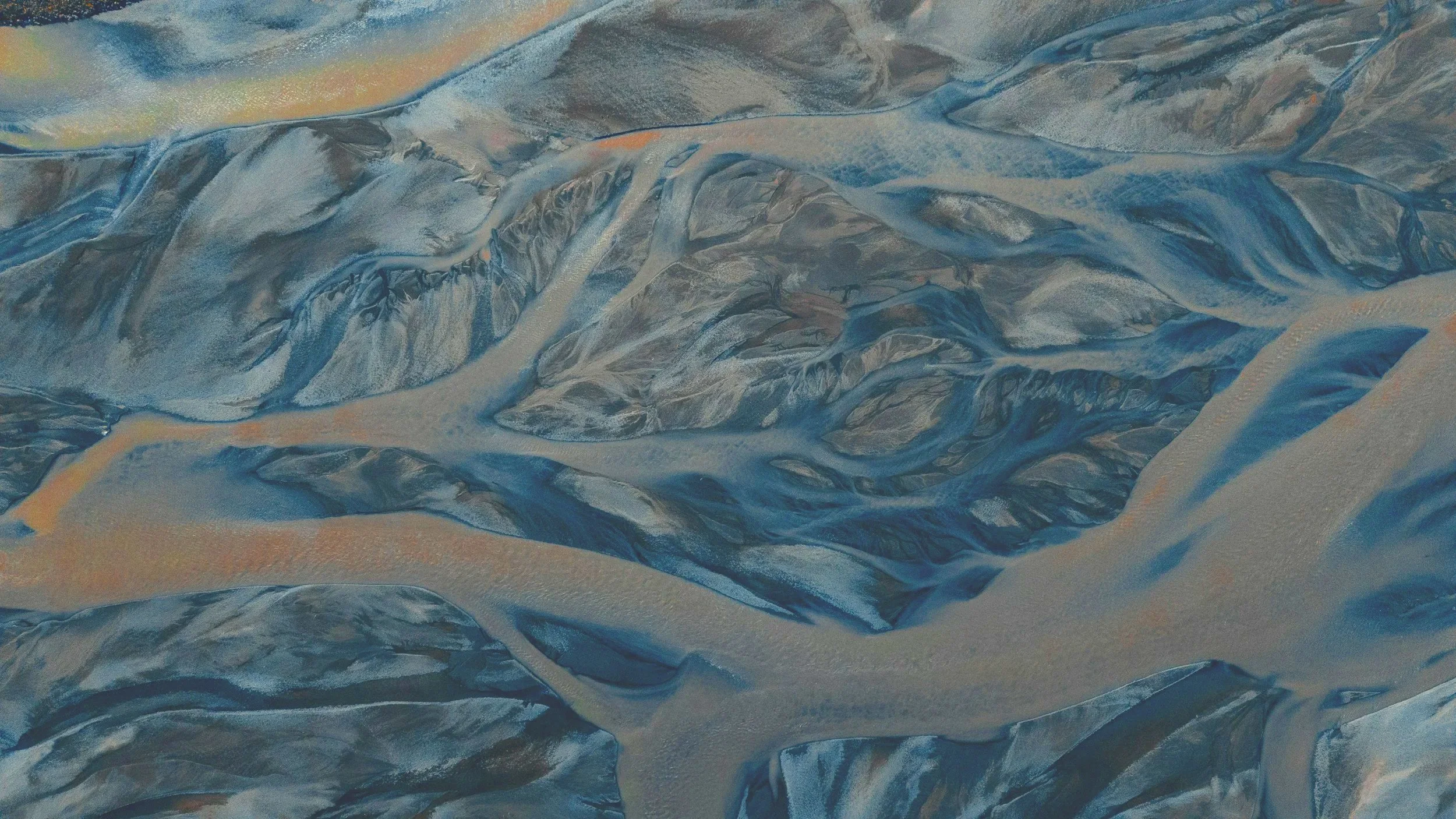 Aerial view of a snow-covered mountain range with winding rivers and valleys.