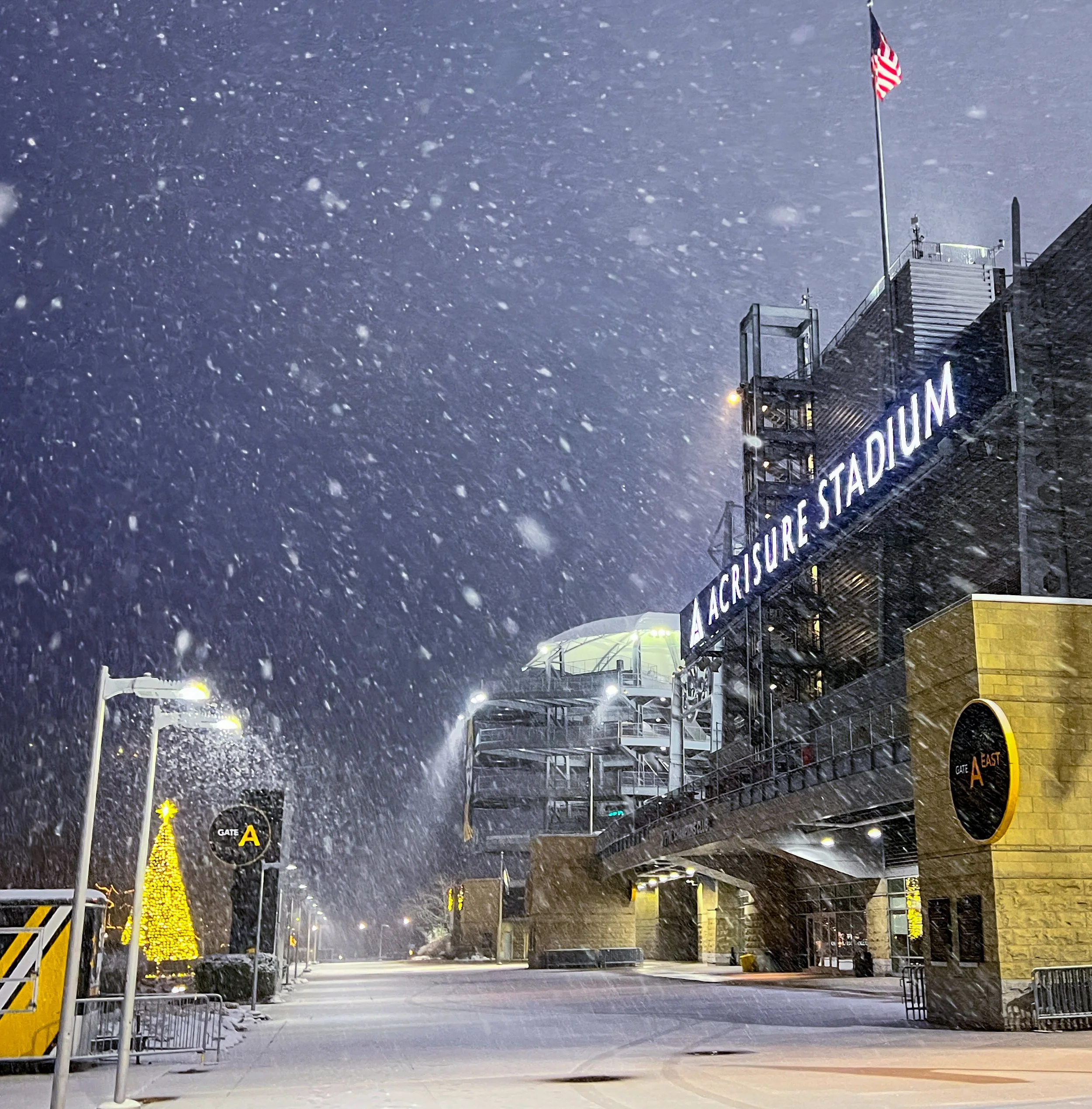 Pittsburgh Steelers Acrisure Stadium snowfall with illuminated buildings at night.