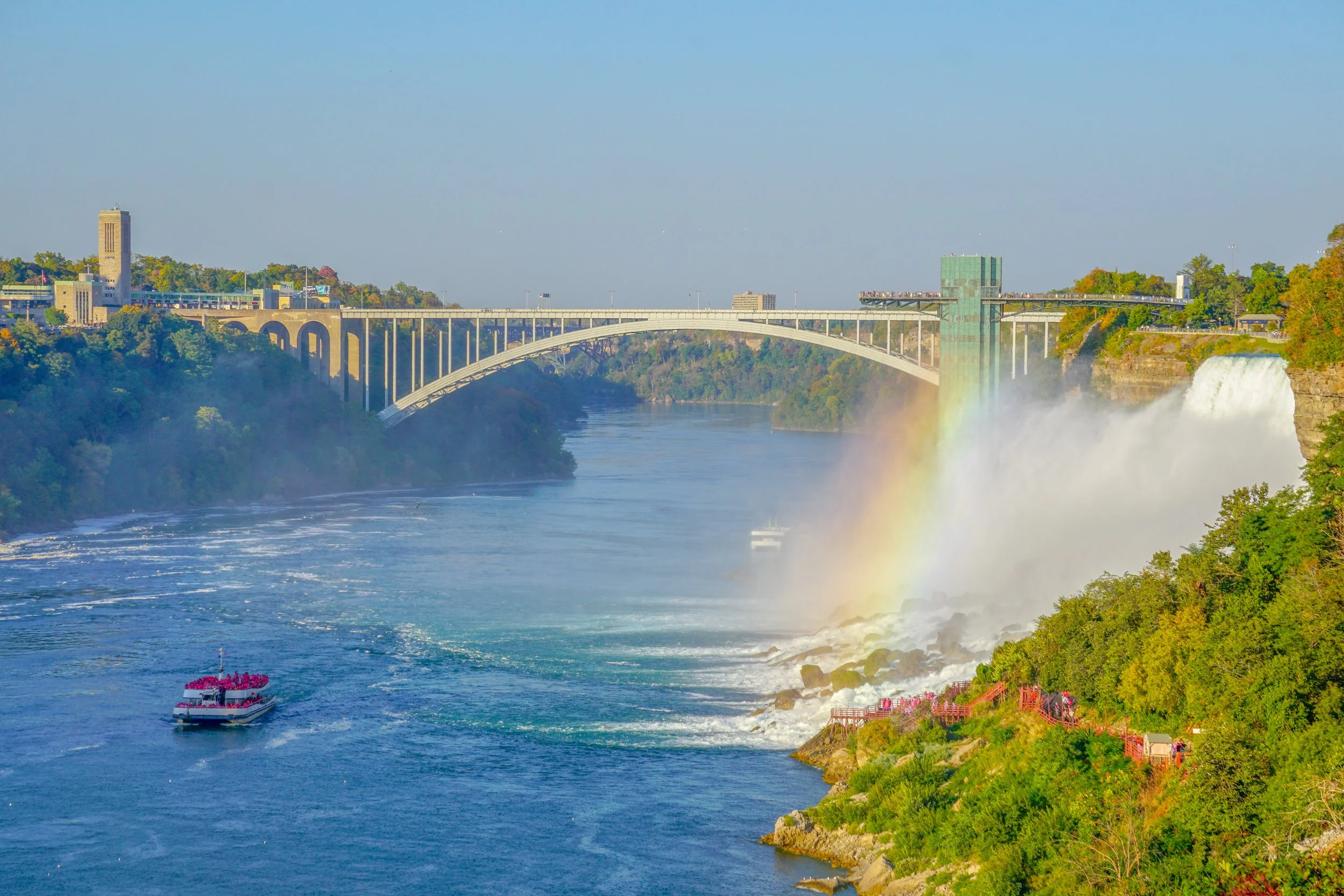 Niagara Falls viewed from the American side with mist and rainbow over the river.