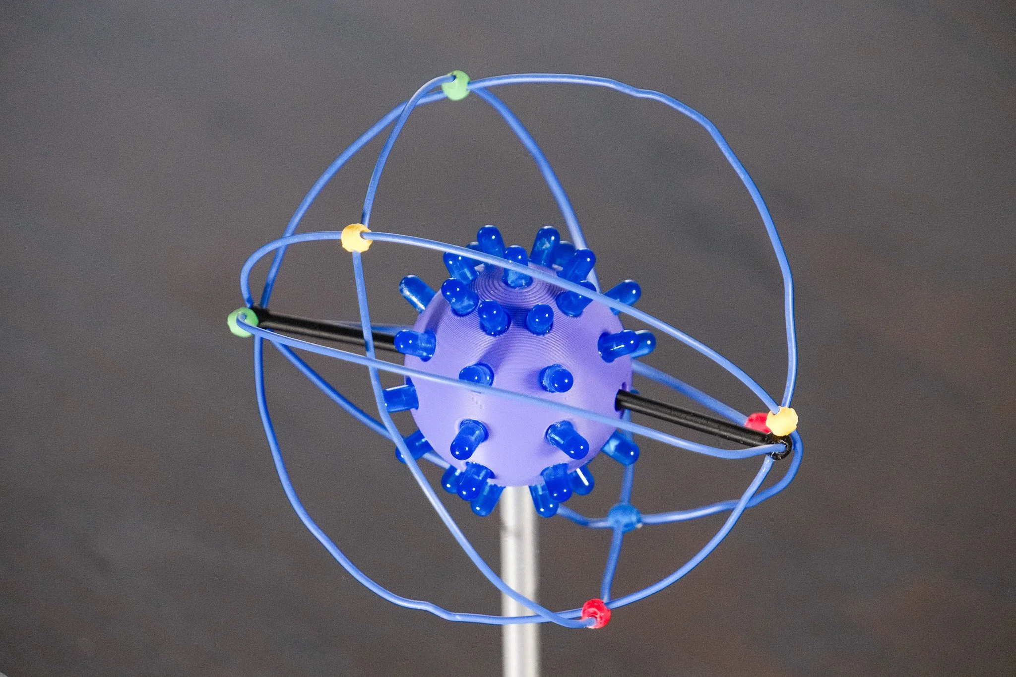 Model of an atom with a purple nucleus and blue electrons orbiting on blue pathways.